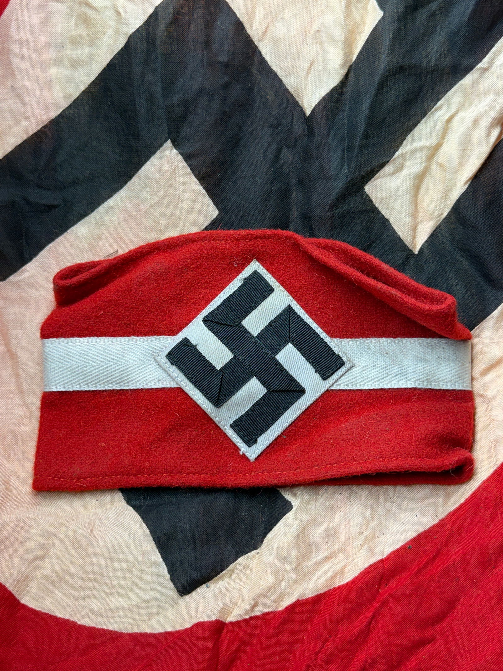 WW2 German Hitler Youth (Hitlerjugend) Armband with RZM Control Tag: This red wool armband bears the black swastika emblem on a white circular field, identifying it as an official armband of the Hitler Youth (Hitlerjugend), the youth organization of Nazi Germany. Such