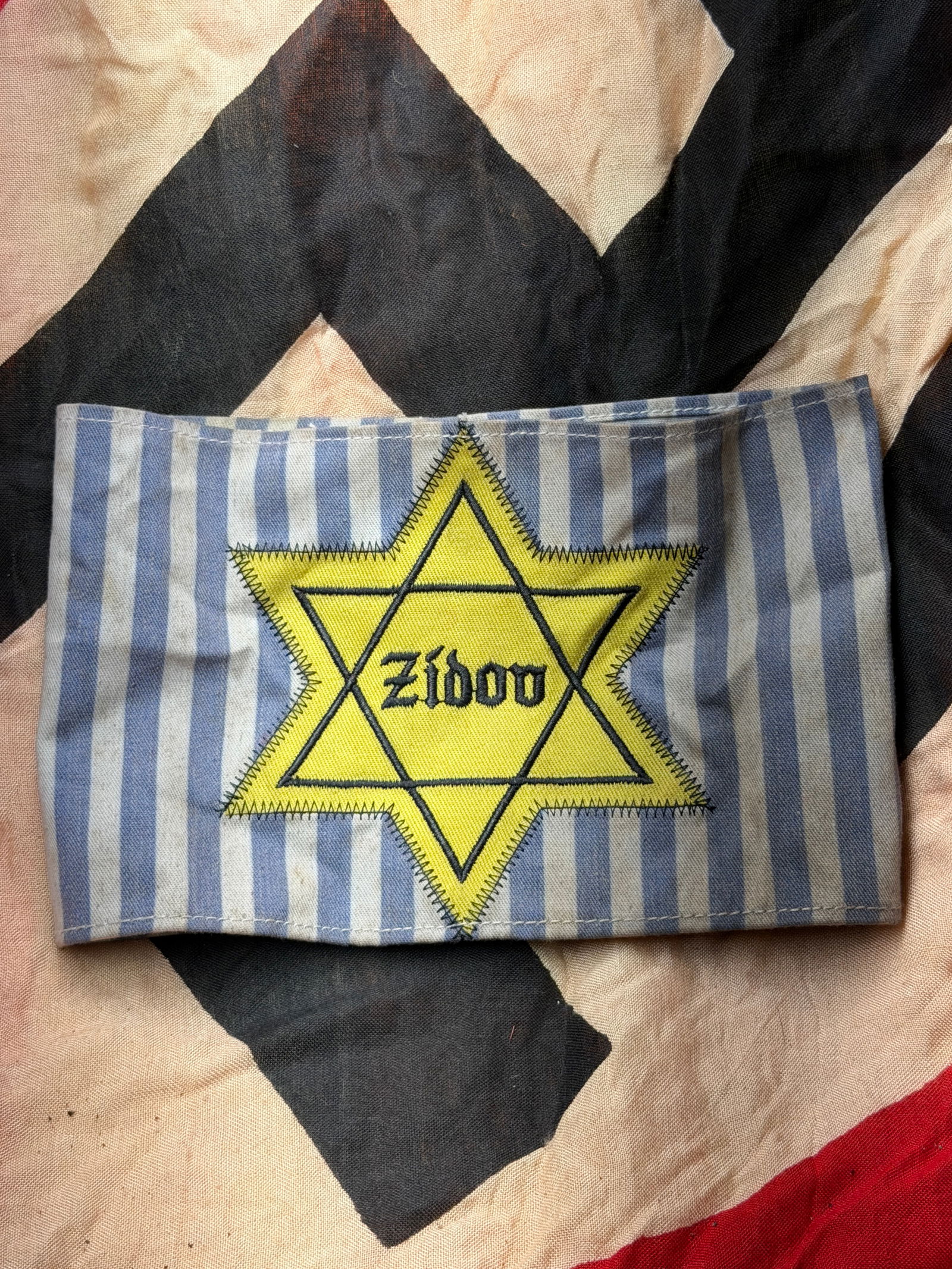 WW2 German Forced Identification Jewish Armband (Yellow Star Of David), Nazi-Occupied Europe: This cloth armband is a compulsory Jewish identification marker imposed by Nazi authorities during the Second World War. Worn on the upper arm, it displays a yellow Star of David bearing the word “Z