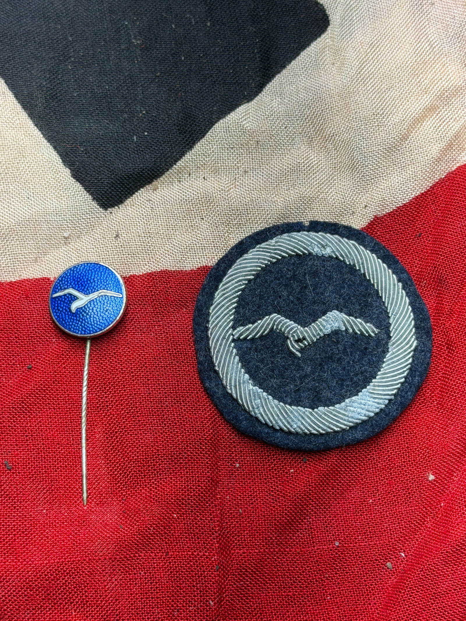 WW2 German Luftwaffe Cloth Qualification Badge & Stick Pin: This circular cloth badge is associated with the German Luftwaffe (Air Force) during the Second World War. Executed in dark blue with a silver-colored embroidered laurel wreath surrounding a stylized