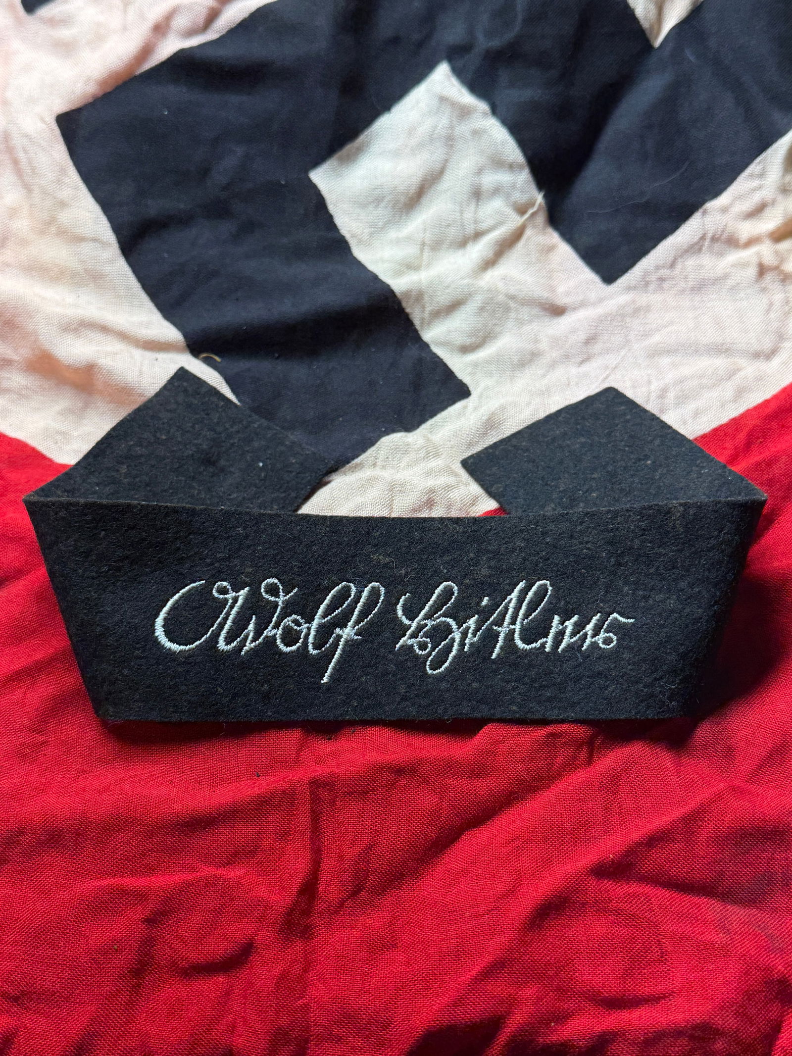 WW2 German SS Cuff Title “Adolf Hitler: World War II–era German SS cuff title bearing the embroidered script “Adolf Hitler”, executed in white thread on a black wool/felt base. This style of cuff title was worn on the lower sleeve