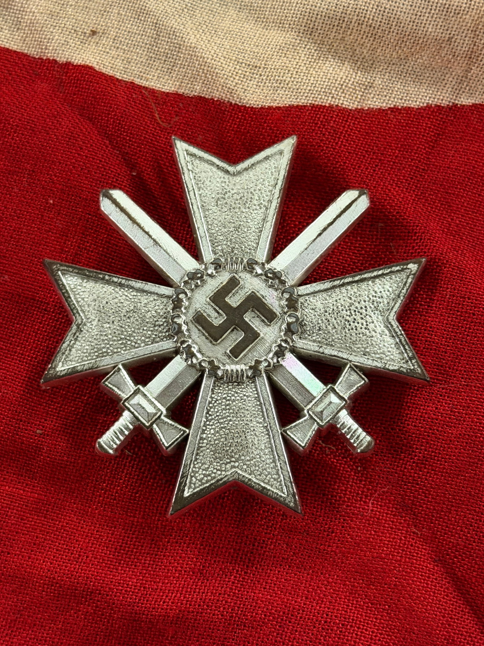 WW2 German War Merit Cross, Second Class with Swords (Germany, 1939–1945): This metal decoration is a War Merit Cross, Second Class with Swords, instituted by Nazi Germany in 1939. The cross-shaped badge bears crossed swords behind the central medallion, signifying recogniti