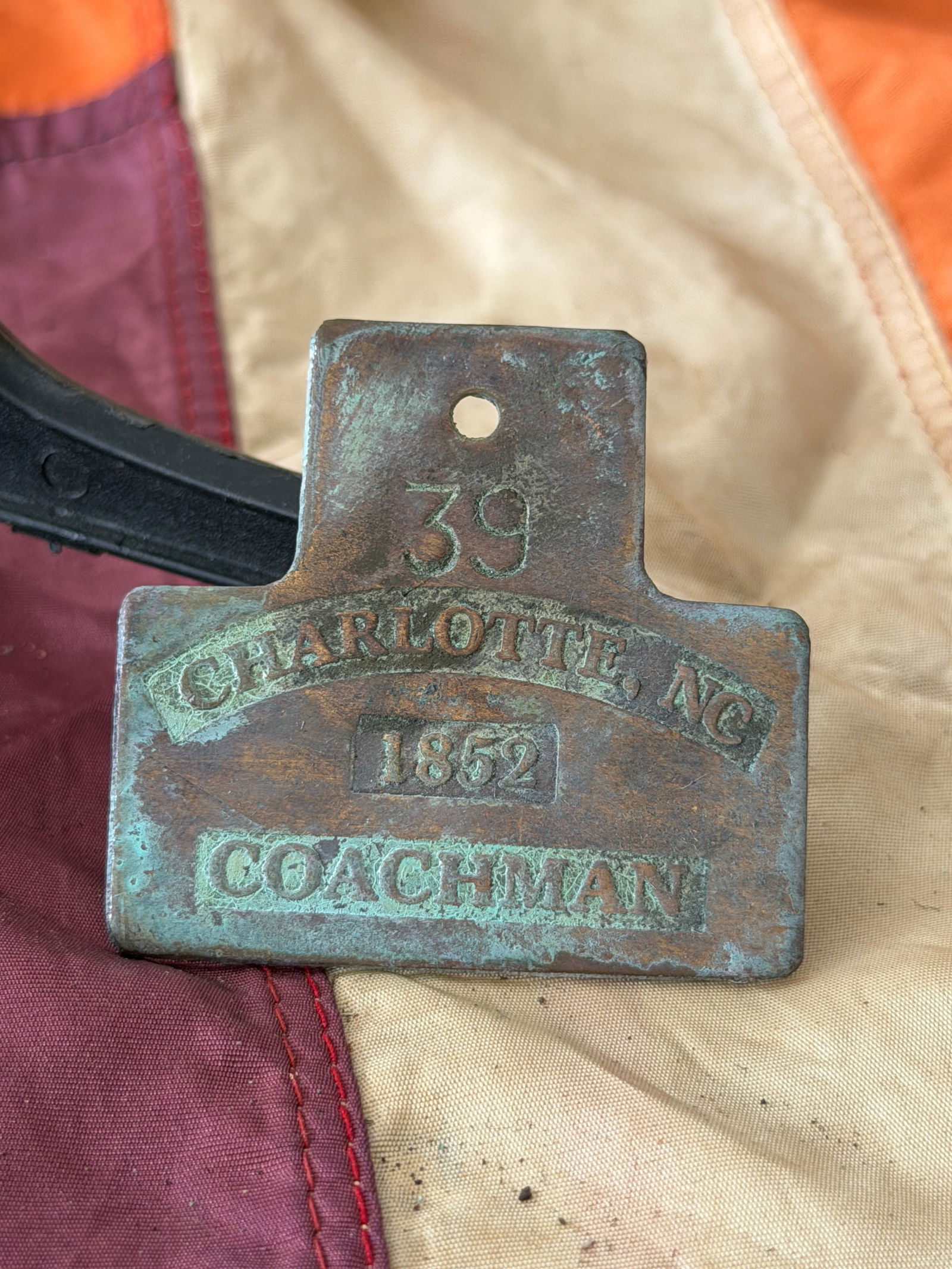 Slave Hire Tag for Coachman, No. 39, Charlotte, North Carolina (1852): This brass slave hire tag, issued in 1852 in Charlotte, North Carolina, is stamped with the occupation “Coachman,” the identification number 39, and the date of issue. Such tags were required