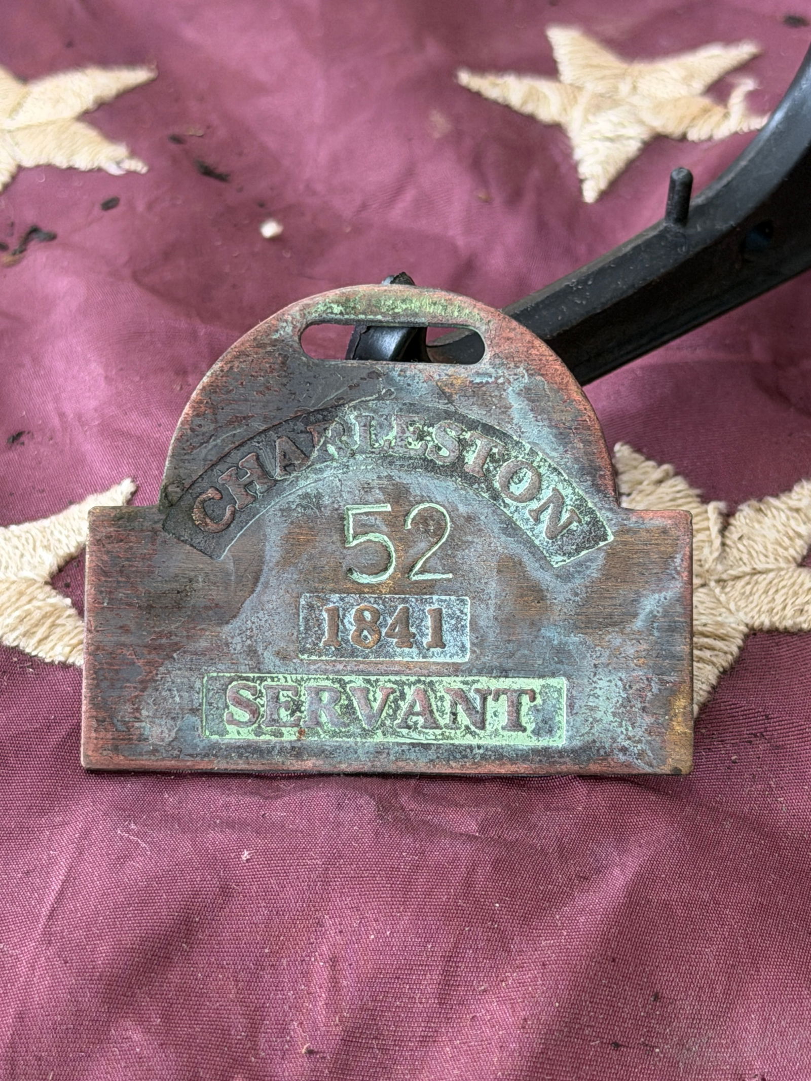 Slave Hire Tag for Servant, No. 52, Charleston, South Carolina (1841): This brass slave hire tag, issued in Charleston, South Carolina, in 1841, bears the identification number 52 and the occupational designation “Servant.” Such tags were mandated by municipal la