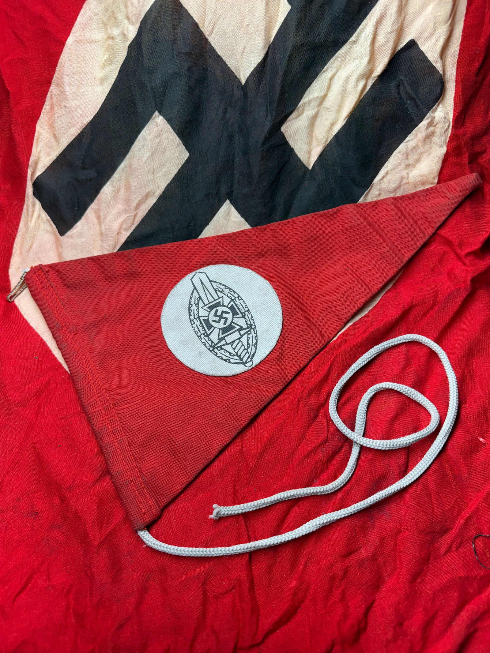 WW2 German NSDAP Political Pennant with Party Badge Emblem: This triangular textile pennant dates to the period of the Third Reich (1933–1945) and is associated with the National Socialist German Workers’ Party (NSDAP). Constructed of red cotton fabric, th