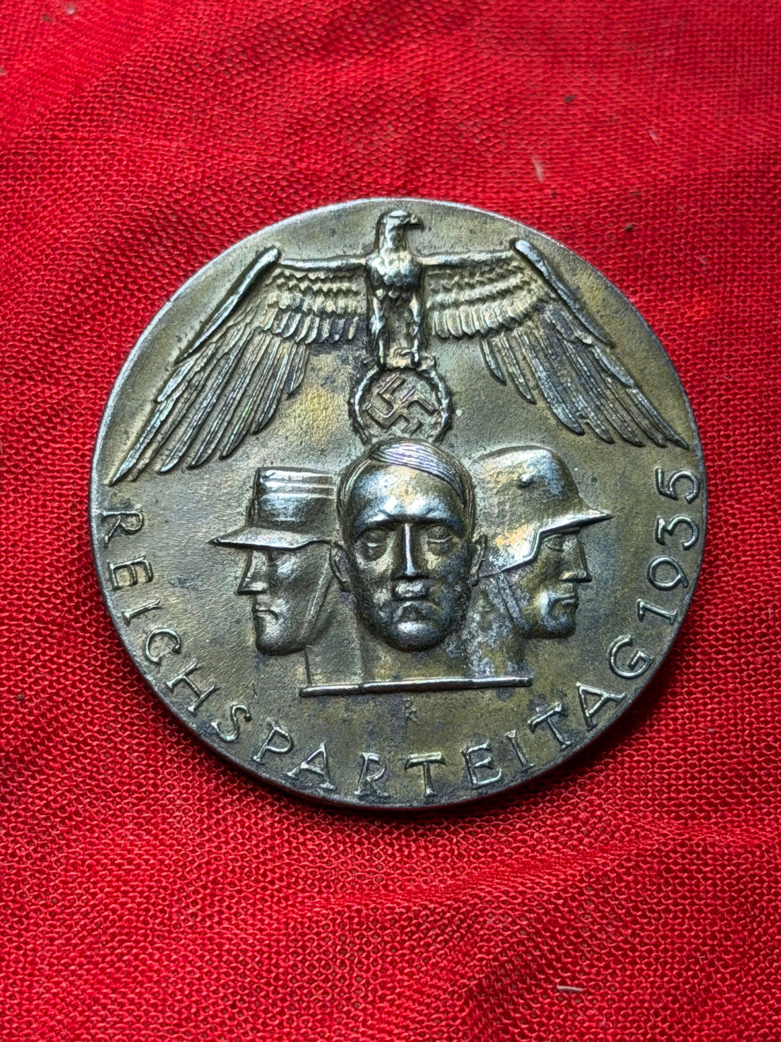 WW2 German Reichsparteitag 1935 Participation Badge (Nuremberg Rally): This circular metal badge was issued to participants of the 1935 Reichsparteitag, the annual National Socialist Party rally held in Nuremberg. The obverse depicts a stylized eagle above three male pro