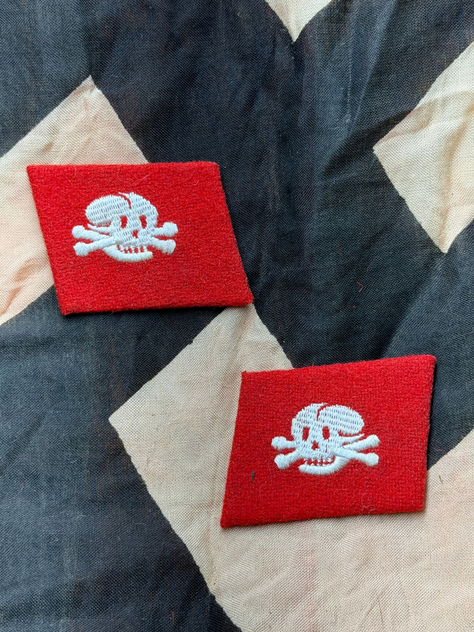 WW2 German SS Totenkopf Collar Tabs (Pair), Third Reich Germany With RZM Paper Tag: This matched pair of red SS Totenkopf (“Death’s Head”) collar tabs features the silver-embroidered skull-and-crossbones emblem worn by members of the SS formations associated with concentrat