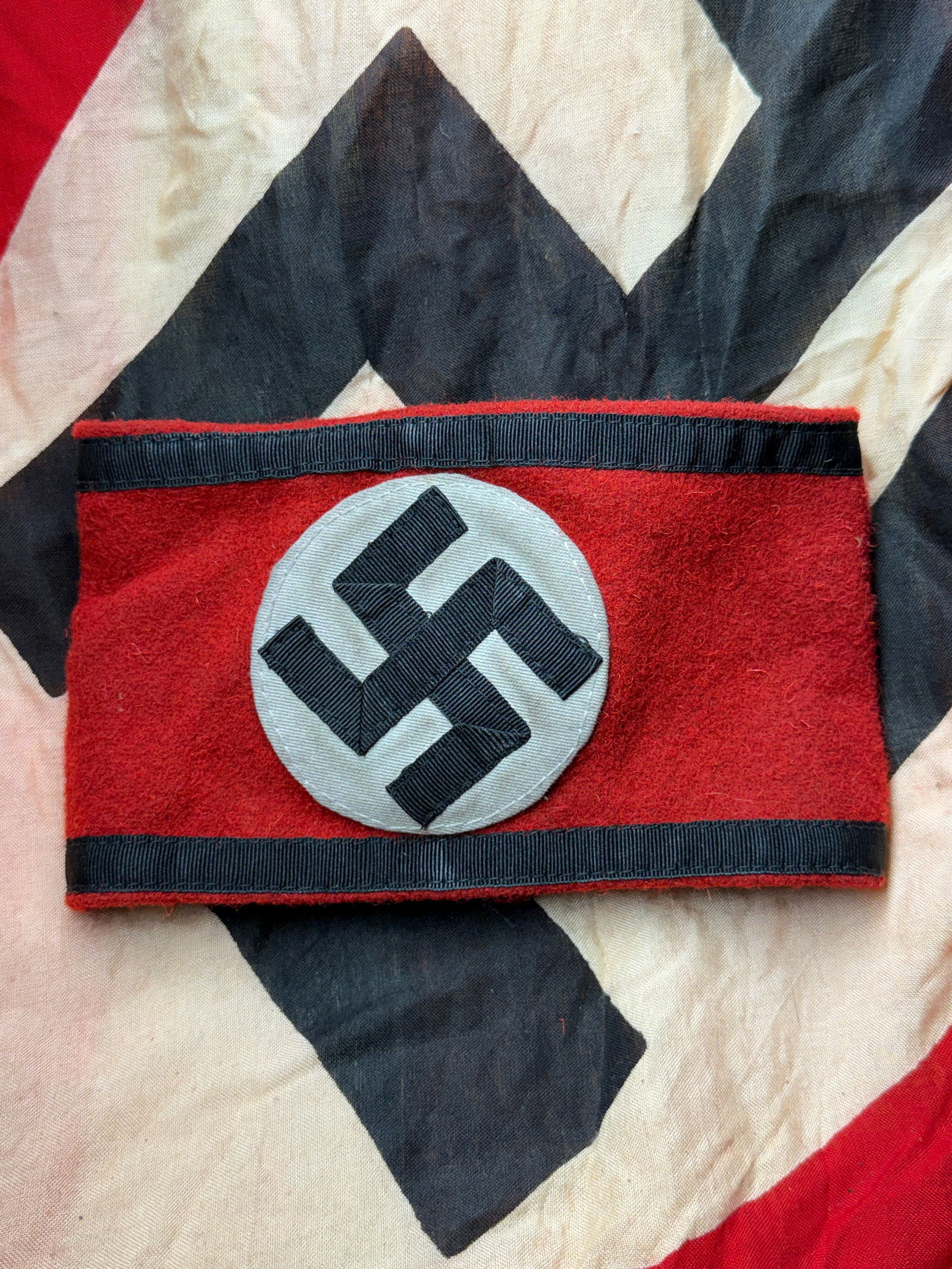 WW2 German Waffen-SS Armband with RZM Authentication Tag: This armband was worn by a member of the Waffen-SS, the armed combat branch of the Schutzstaffel (SS) during the Second World War. The red wool field with a white roundel and black swastika served as
