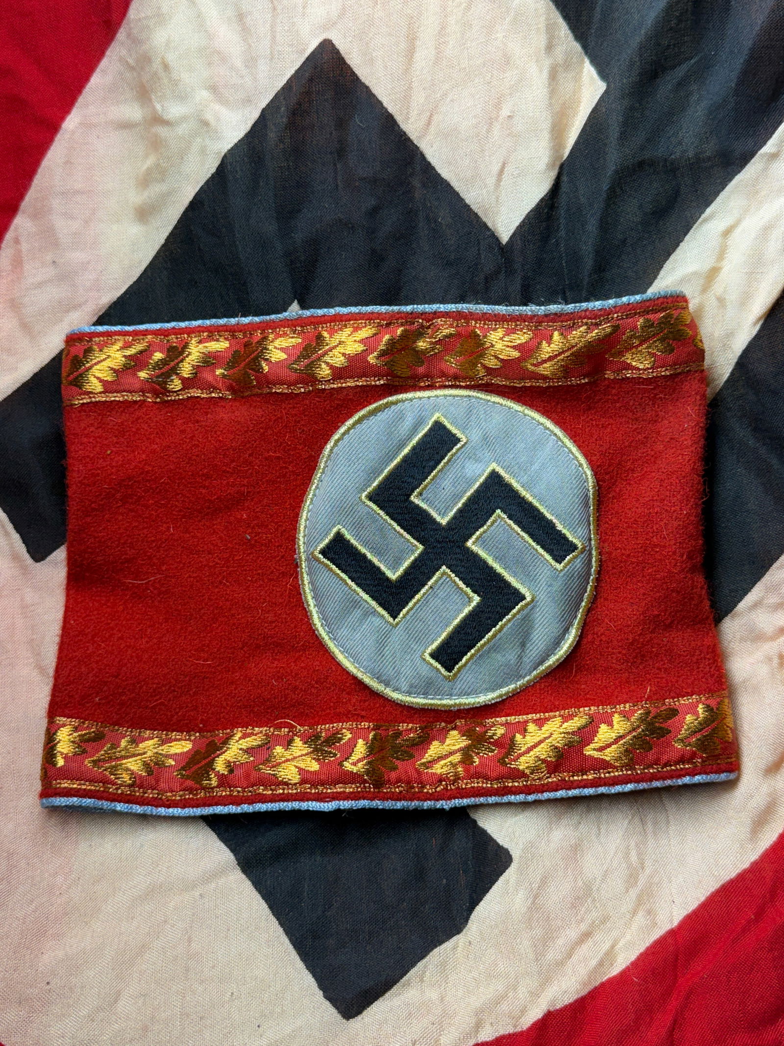 WW2 German National Socialist Party Armband (Political Leader Variant) With RZM Paper Tag: This armband is an political insignia of the National Socialist German Workers’ Party (NSDAP), produced in Germany during the Third Reich period (1933–1945). Constructed from red wool with applied
