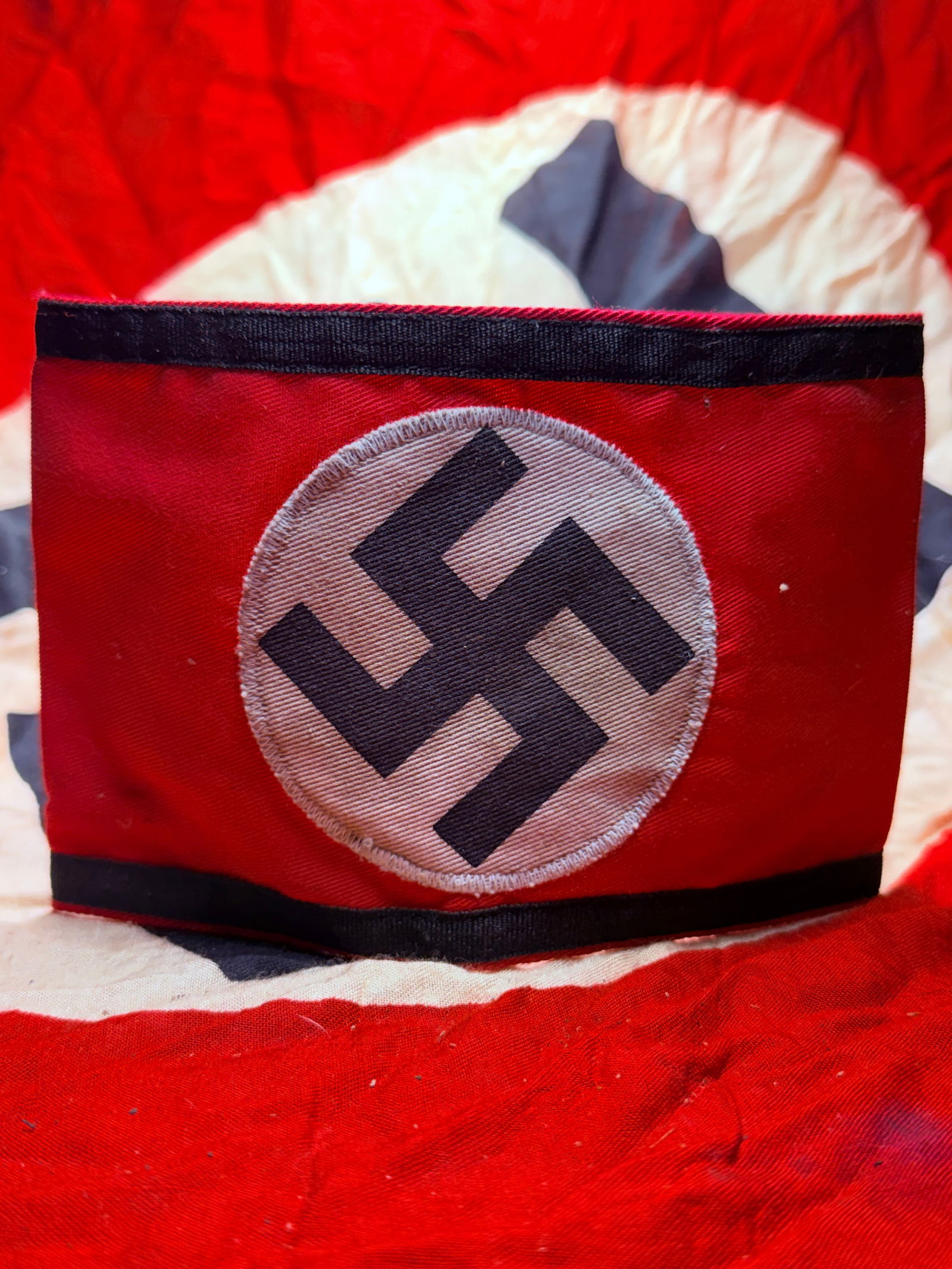 WW2 German National Socialist Party (NSDAP) Political Armband: This red armband bearing a white roundel with a black swastika is an example of a German National Socialist Party (NSDAP) political armband from the Second World War period. Such armbands were worn by