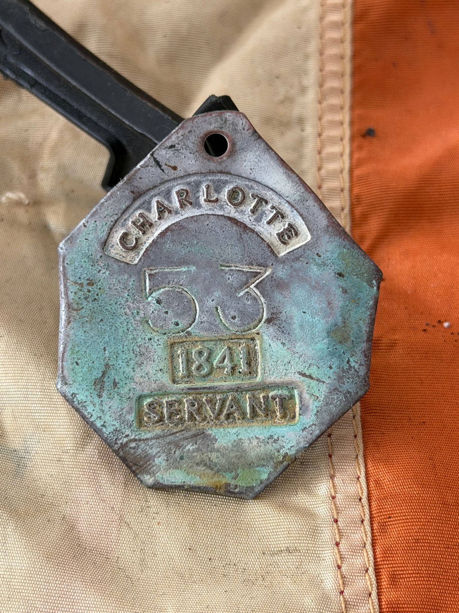 Charleston “Servant?? Registration Badge Slave Tag, No. 53 (1841): This octagonal copper-alloy registration badge was issued in Charleston, South Carolina, in 1841 and stamped “CHARLOTTE / 53 / 1841 / SERVANT.” Such badges were part of a municipal system that