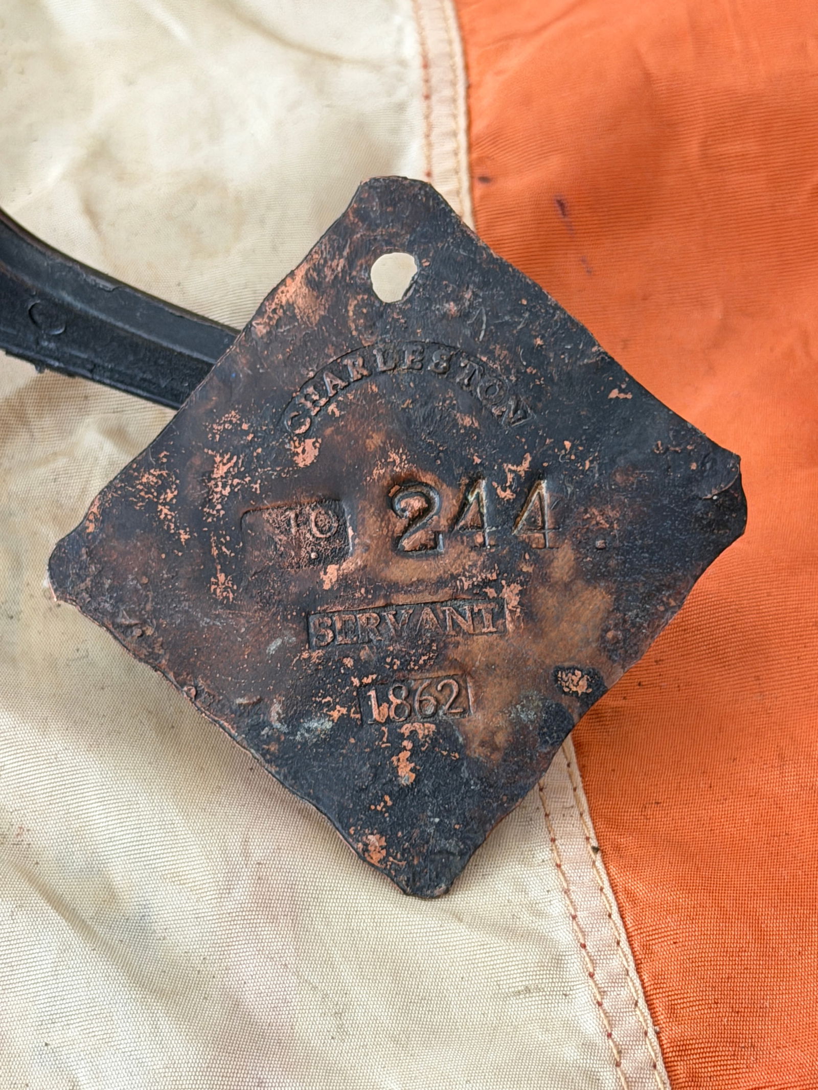 Charleston Slave Hire Tag Servant Id No. 244 (1862): This copper-alloy slave hire tag was issued in Charleston, South Carolina, in 1862, during the American Civil War. Stamped with the city name “CHARLESTON,” the registration number “244,&rdqu