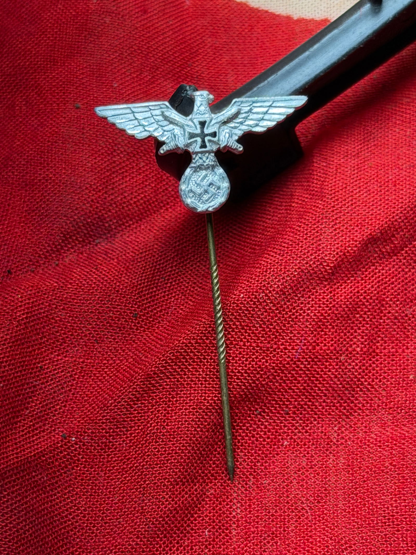 WW2 German Reichsadler Stickpin (Political Eagle Insignia): This small metal stickpin depicts the Reichsadler (Imperial Eagle) clutching a wreath enclosing a swastika—an emblem widely used by the National Socialist state and its affiliated organizations. Pro