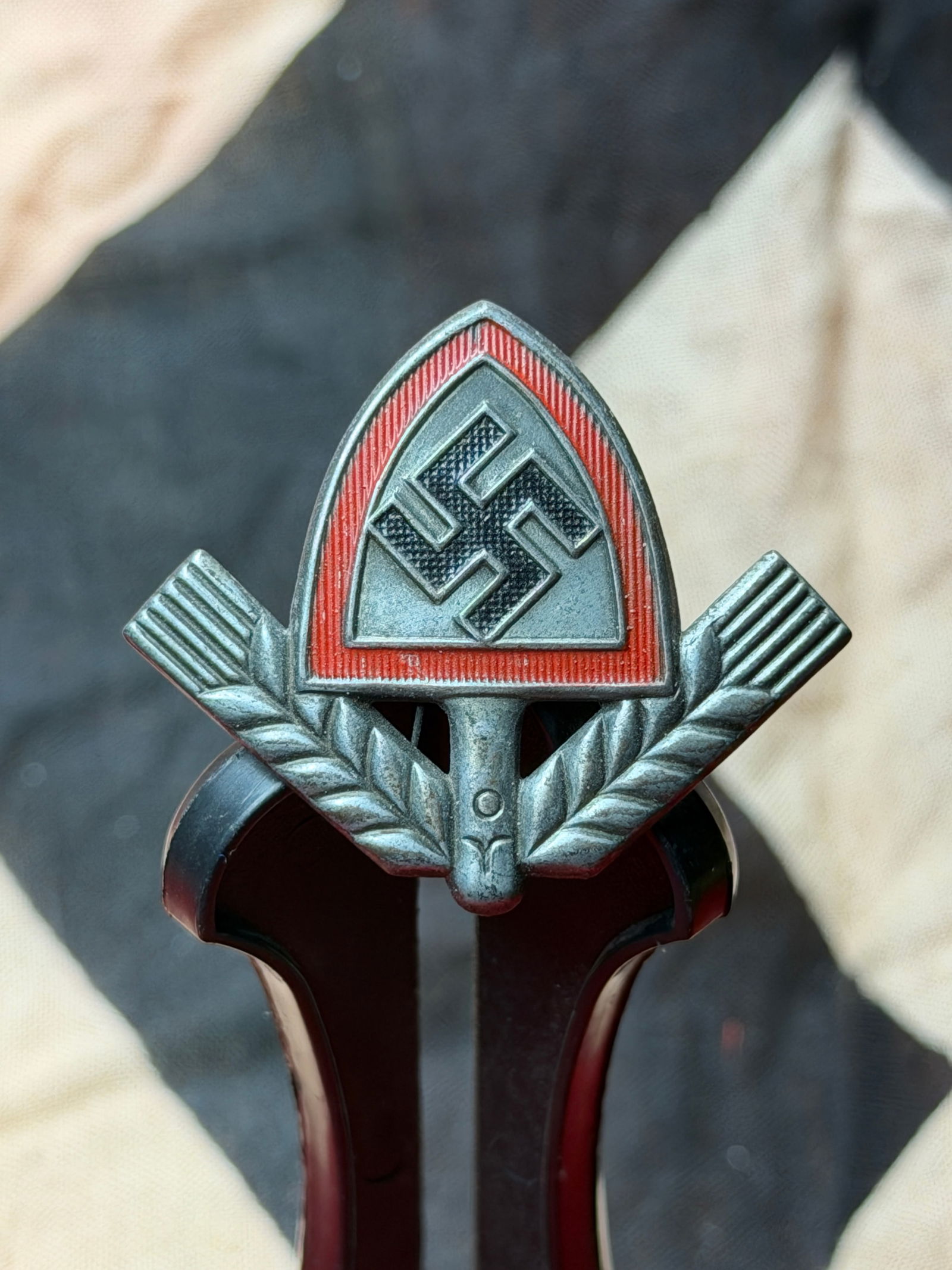 Reich Labour Service Youth (RADj) Cap Badge - Maker Marked: This metal cap badge was worn by members of the Reichsarbeitsdienst der Jugend (RADj), the youth branch of the Reich Labour Service in Nazi Germany during the Second World War (1939–1945). The RAD f