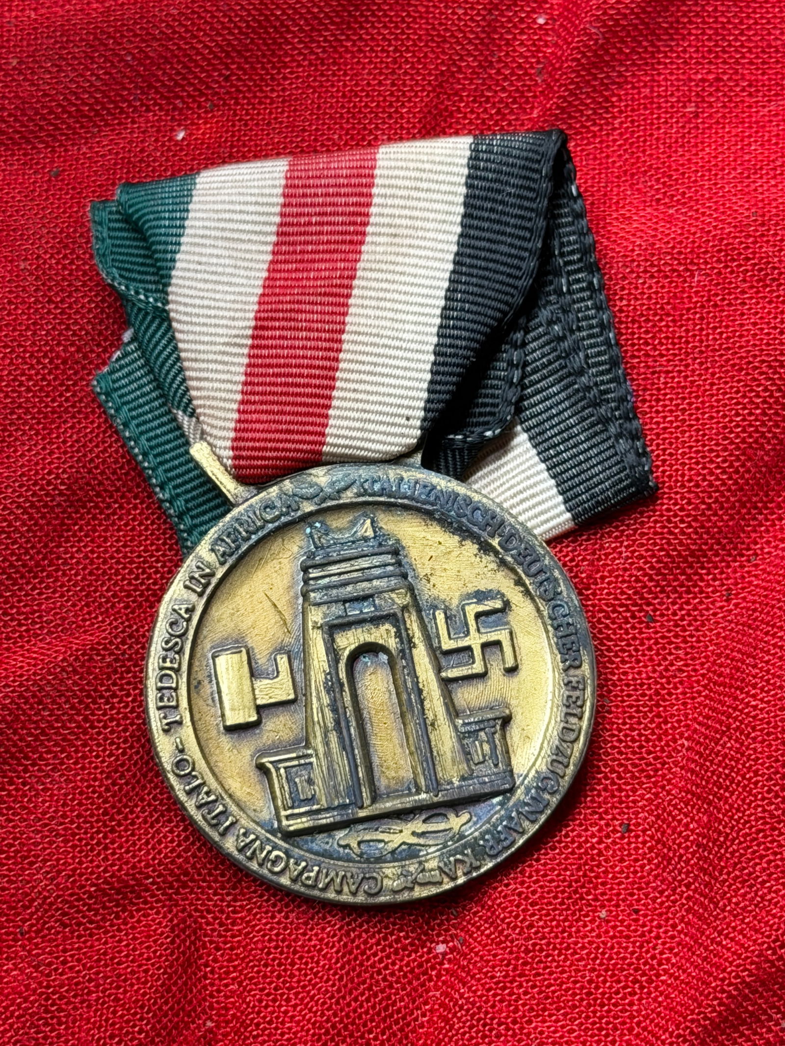 WW2 German Faithful Service in the Reich: German Campaign Medal, 1939–1945: This medal is a World War II–era German campaign award, suspended from a tri-color ribbon and struck in metal with relief imagery. One side depicts monumental architecture flanked by period symbols,