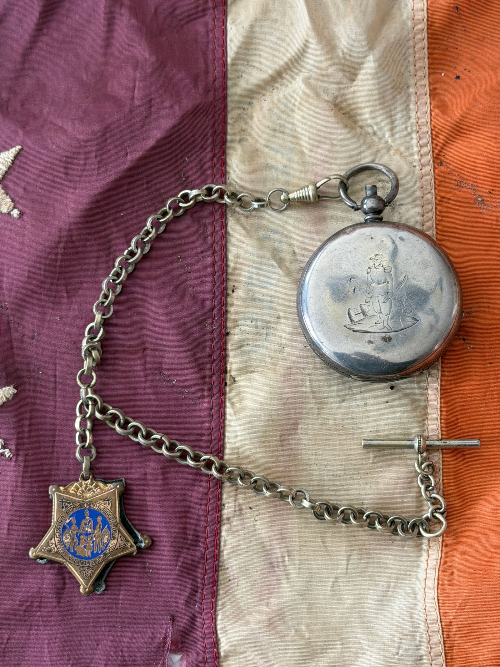 Civil War–Era Pocket Watch with Grand Army of the Republic Medal and Chain: This Civil War–era pocket watch is accompanied by a period watch chain and an ornate Grand Army of the Republic (G.A.R.) membership medal, reflecting both wartime service and postwar remembrance. Th