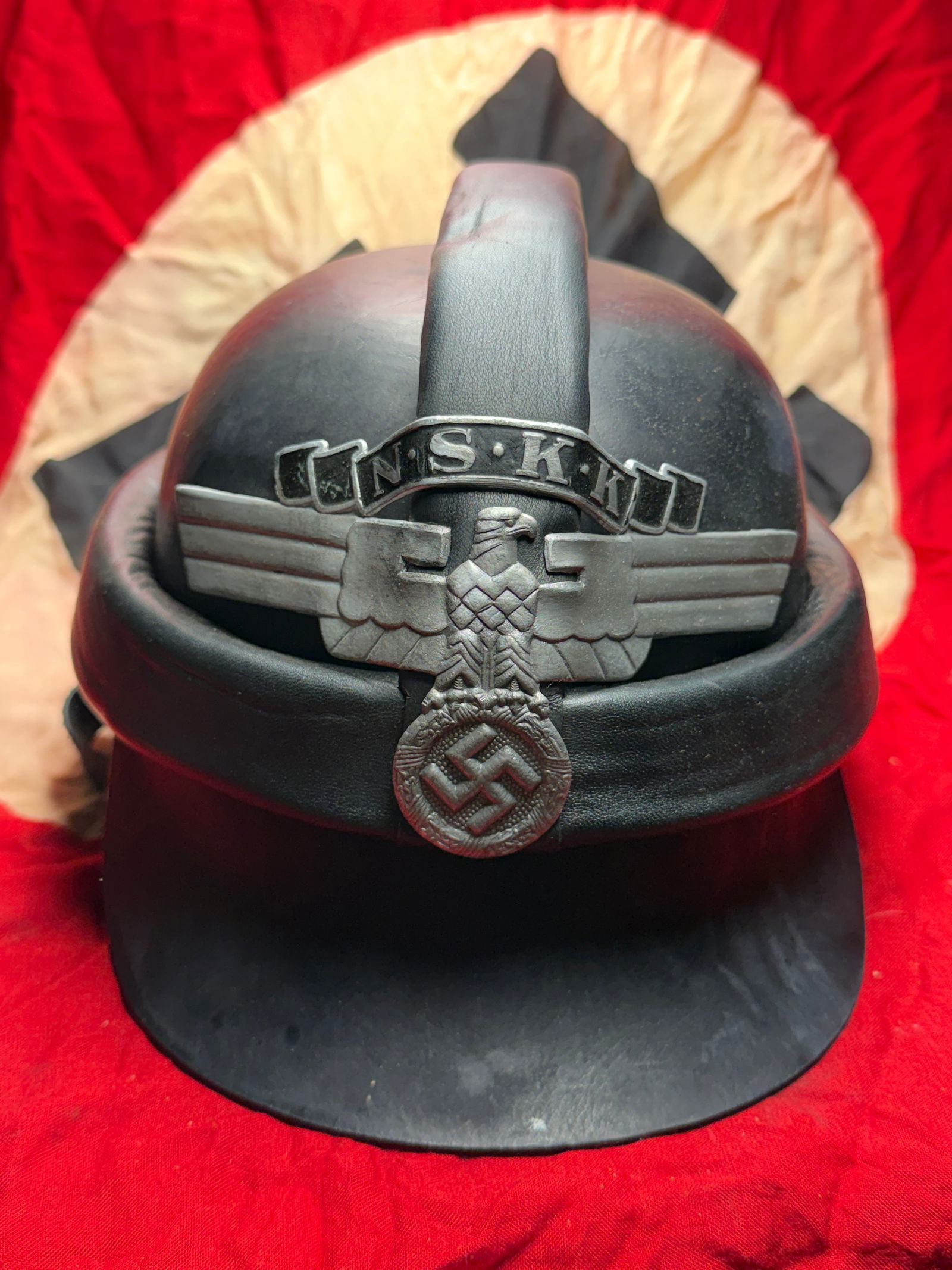 WW2 German National Socialist Motor Corps (NSKK) Crash Helmet (Sturzhelm): This black leather Sturzhelm (crash helmet) was issued to members of the Nationalsozialistisches Kraftfahrkorps (NSKK), a paramilitary organization of Nazi Germany responsible for motor transport trai