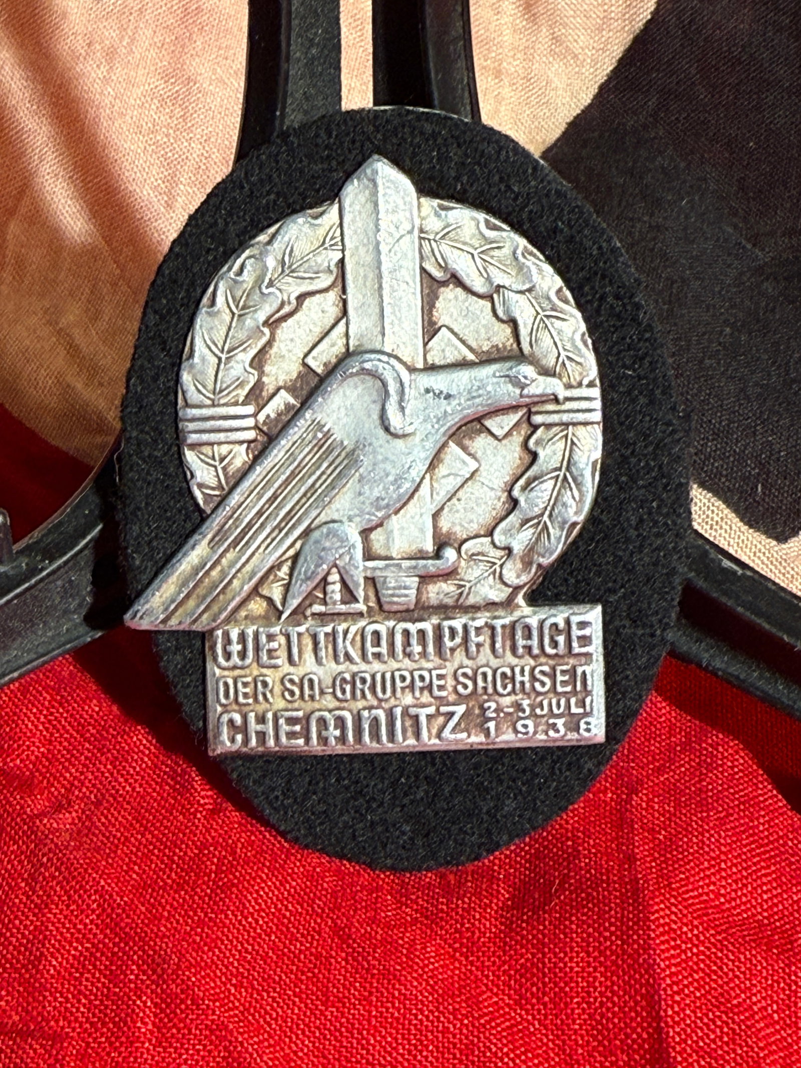 WW2 German SA Group Saxony Competition Days Badge BY RZM (Wettkampftage der SA-Gruppe Sachsen),: RZM maker marked Silver-colored commemorative badge mounted on a black cloth backing for the Wettkampftage der SA-Gruppe Sachsen (SA Group Saxony Competition Days) held in Chemnitz on July 2–3, 1938