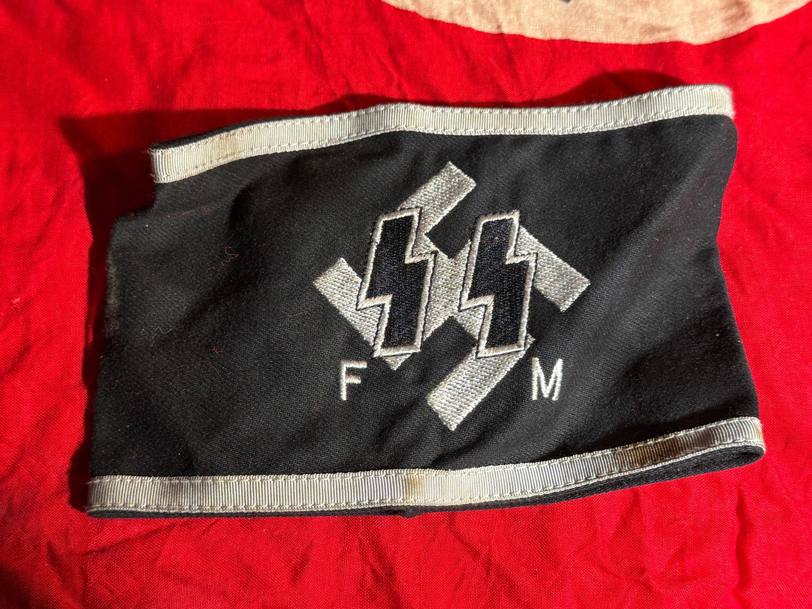 WW2 German SS Supporting Members Armband With RZM Paper Tag (Fördernde Mitglieder der SS), Nazi: Black cloth armband bearing embroidered silver SS runes over a diagonal swastika field with the letters “F M,” denoting Fördernde Mitglieder (Supporting Members of the SS). These individuals