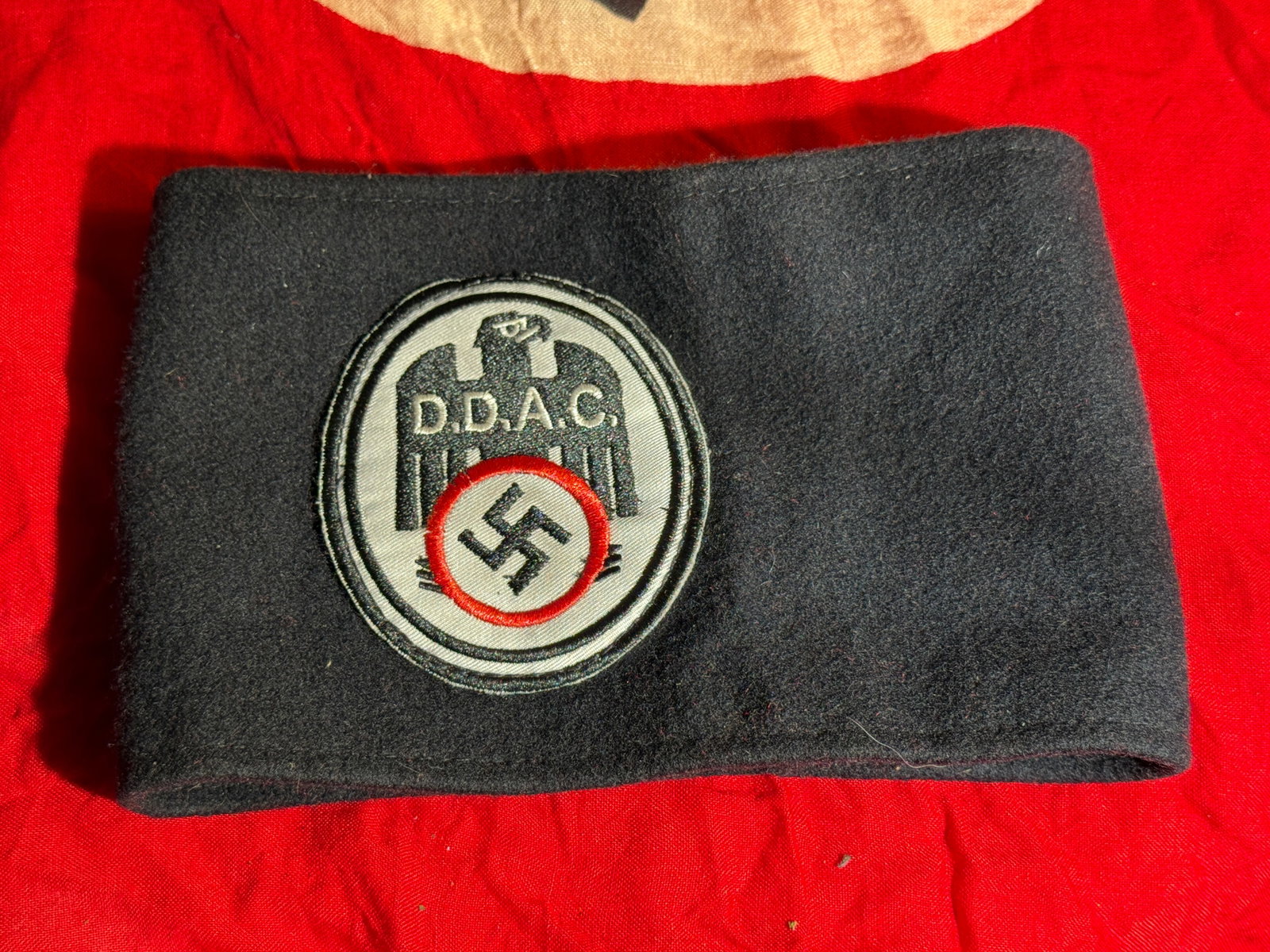 WW2 German DDAC Armband (Der Deutsche Automobil-Club), Nazi Germany, c. 1933–1945: Black cloth DDAC (Der Deutsche Automobil-Club) armband featuring the organization’s emblem: a stylized eagle above the initials “D.D.A.C.” and a swastika within a circular border. The DDAC s