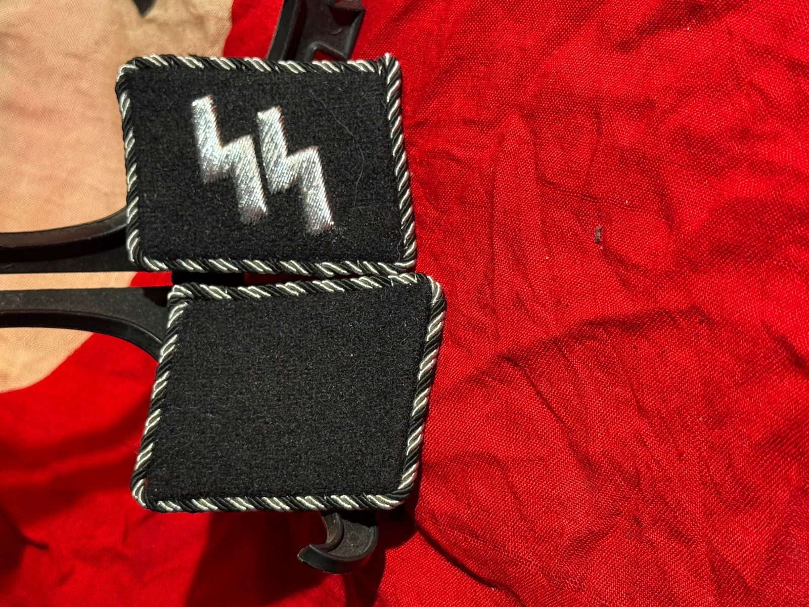 WW2 German Waffen-SS Enlisted Collar Tab with SS Runes And RZM Paper Tag, Third Reich: Black wool Waffen-SS enlisted collar tab embroidered with the distinctive SS double-sig rune insignia in silver thread, worn on the right collar of SS uniforms to denote membership in the Schutzstaffe