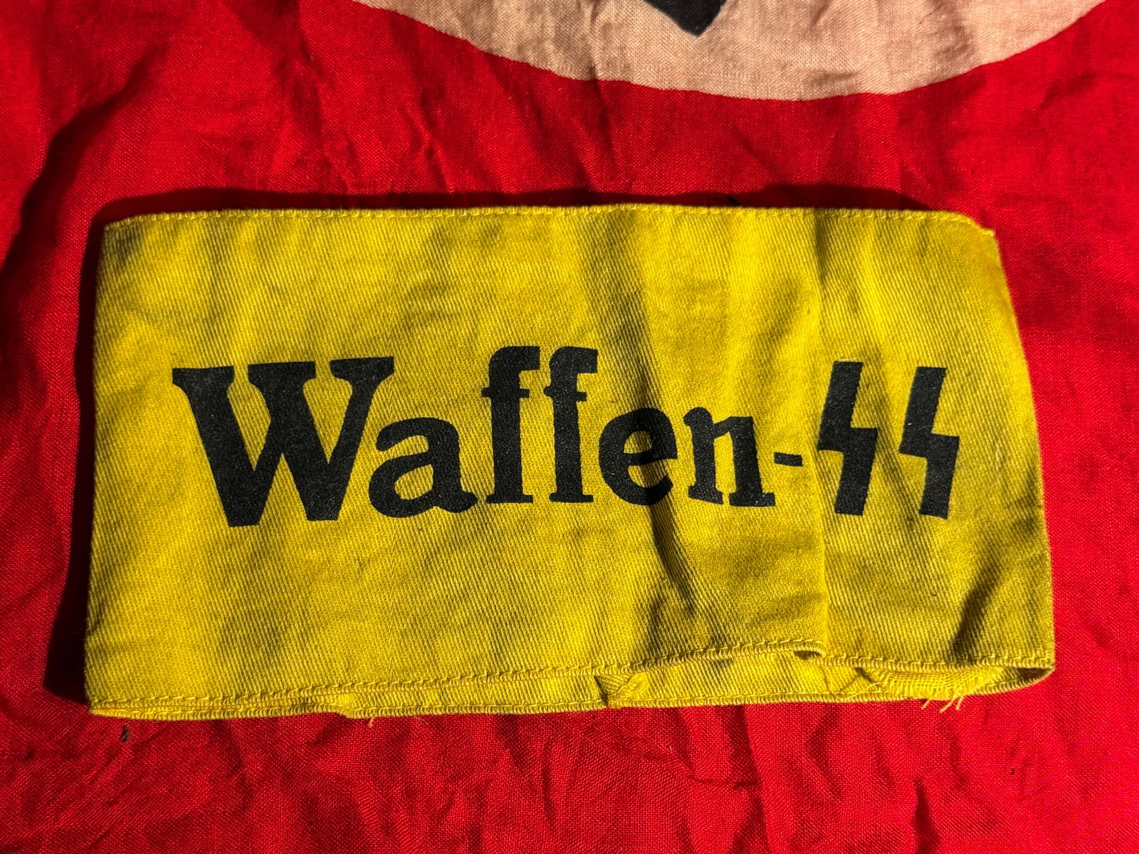 WW2 German Waffen-SS Identification Armband (Waffen-SS), RZM Issue, Third Reich With RZM Paper Tag: Yellow cloth Waffen-SS identification armband printed with the inscription “Waffen-SS” and SS runes in black. Interior retains the original RZM control label (Reichszeugmeisterei) marked with