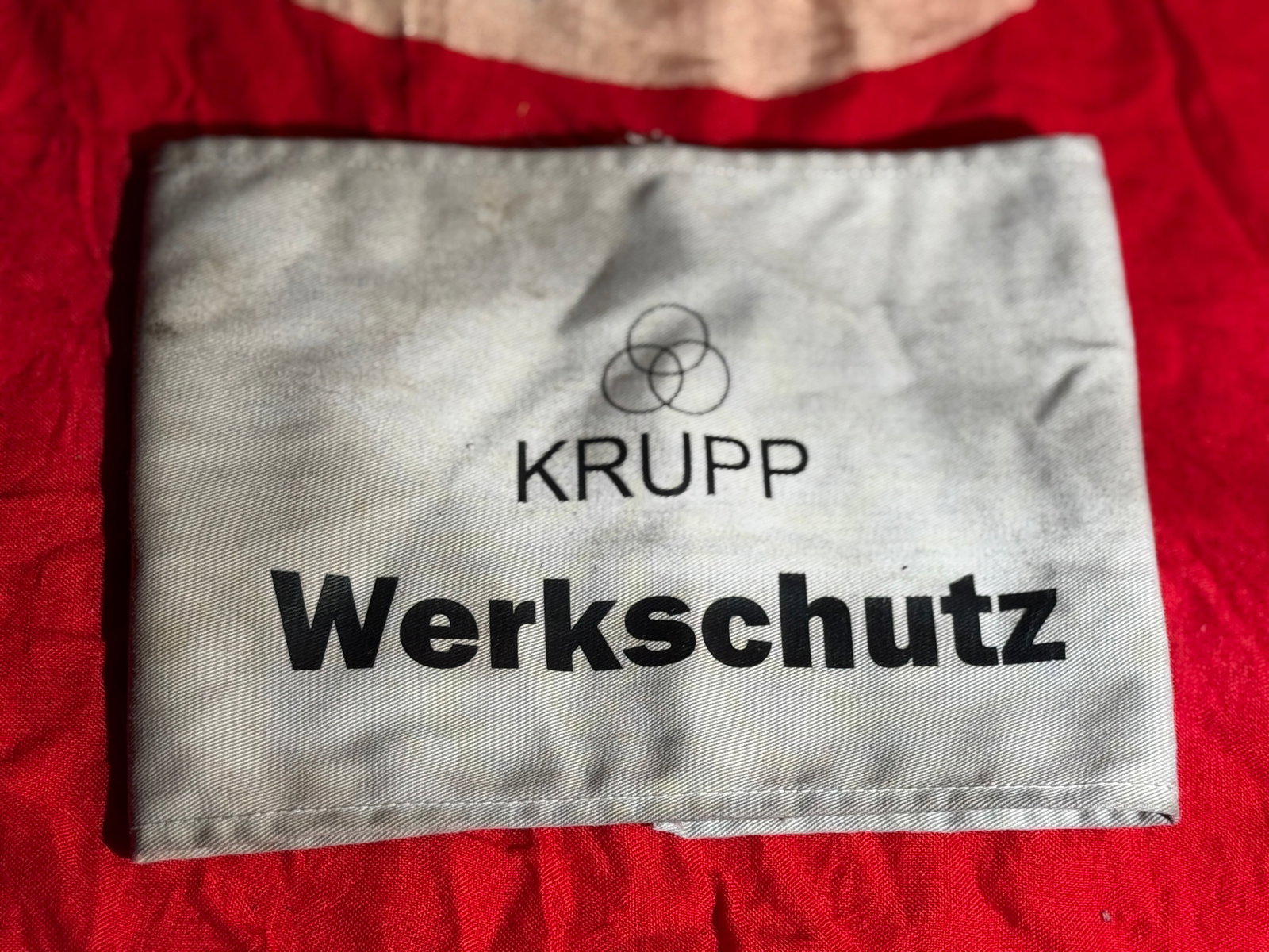 WW2 German Krupp Werkschutz Factory Guard Armband, Germany, 1942: Cloth Werkschutz (factory security) armband issued by the German industrial company Krupp during the Second World War. The armband bears the Krupp corporate logo above the word “Werkschutz” (G