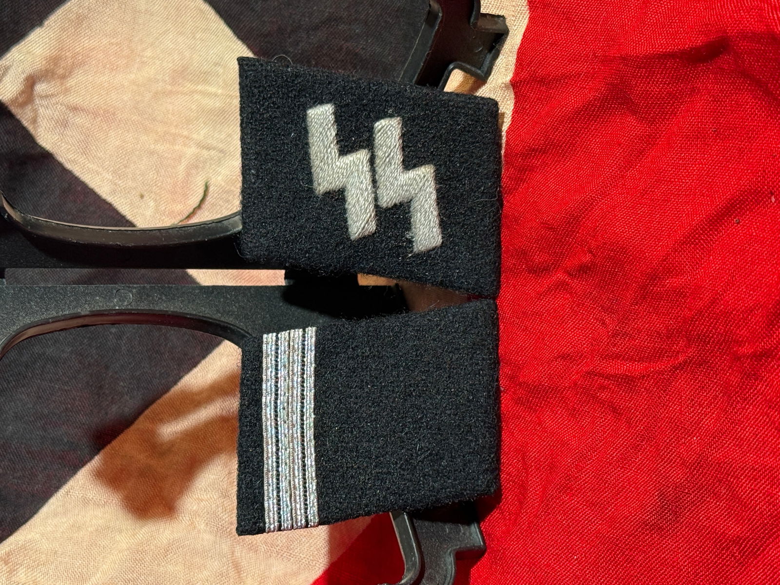 WW2 German Waffen-SS Enlisted Man’s Shoulder Boards with SS Collar Tab With RZM Paper Tag: This set consists of Waffen-SS enlisted rank insignia, including a pair of black wool shoulder boards with silver rank piping and a black SS collar tab embroidered with the double Sig-rune insignia. T