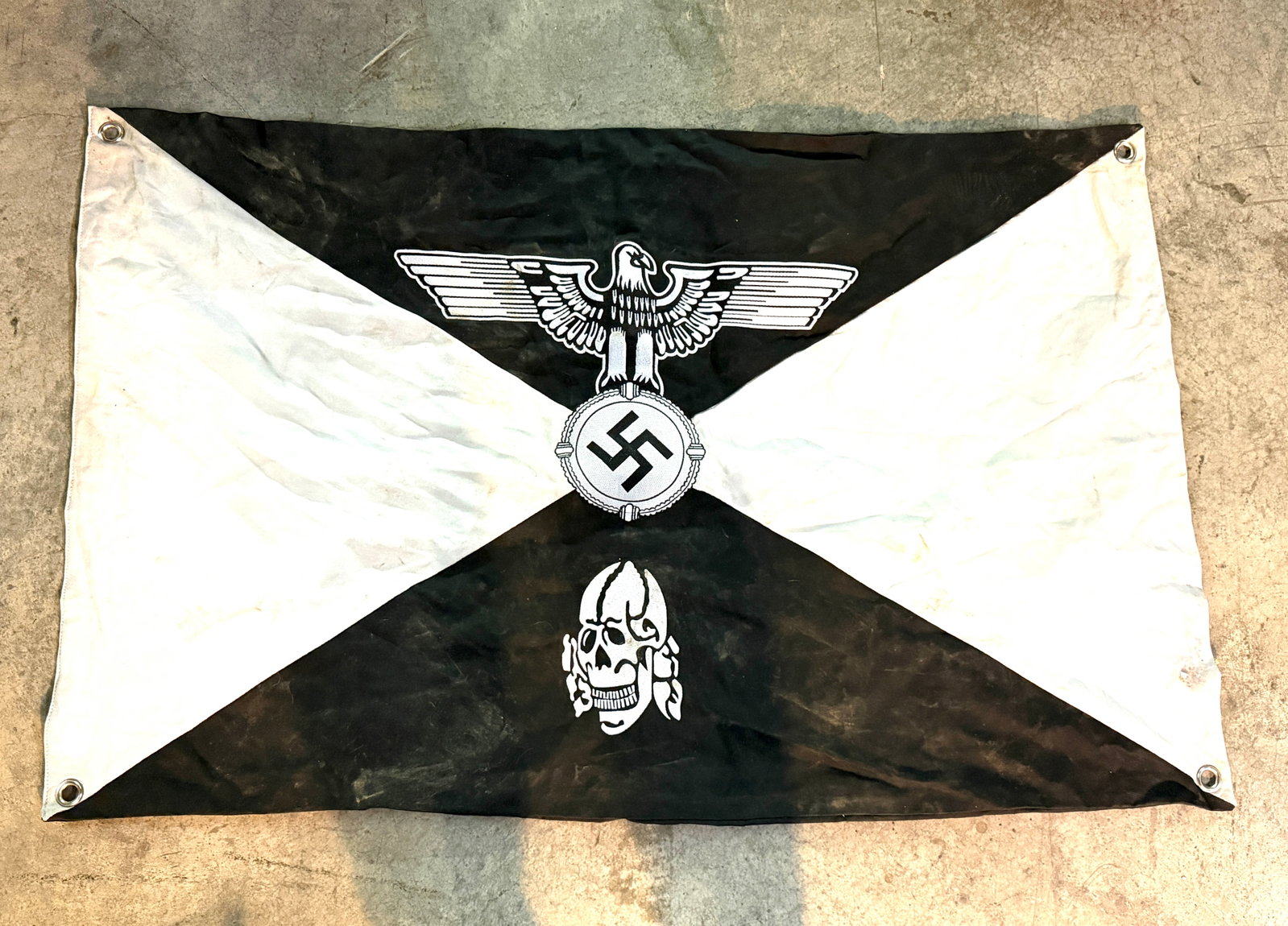 Scarce WW2 German Third Reich SS Totenkopf Banner: This black-and-white banner features imagery associated with Nazi Germany, including a Reich eagle clutching a swastika and a Totenkopf (death’s head) skull motif, symbols historically used by the S