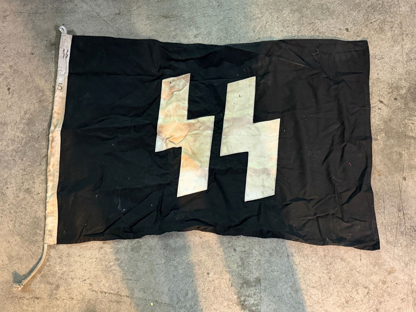WW2 German SS Double-Sig Rune Flag (Schutzstaffel): This black banner displays the SS “Sig” runes, the distinctive double lightning-bolt emblem used by the Schutzstaffel (SS), the paramilitary organization of the Nazi regime in Germany during t