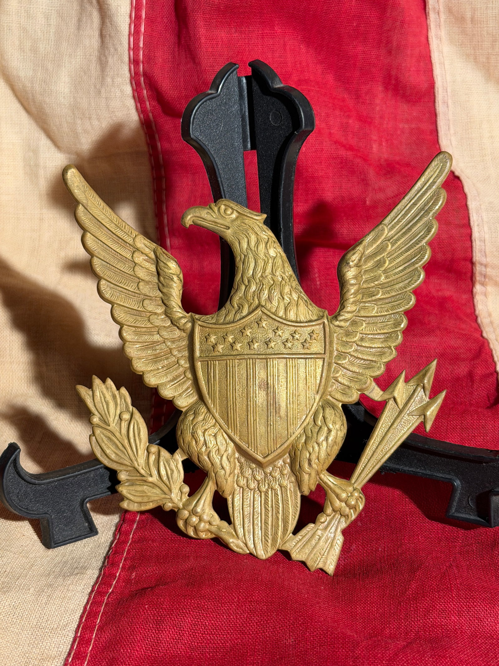 Indian Wars Officer’s Cap Insignia (Great Seal Eagle), Early–Mid 20th Century: This metal insignia depicts the American bald eagle with outstretched wings, clutching an olive branch and arrows, and bearing a shield with thirteen stars and vertical stripes, derived from the Great