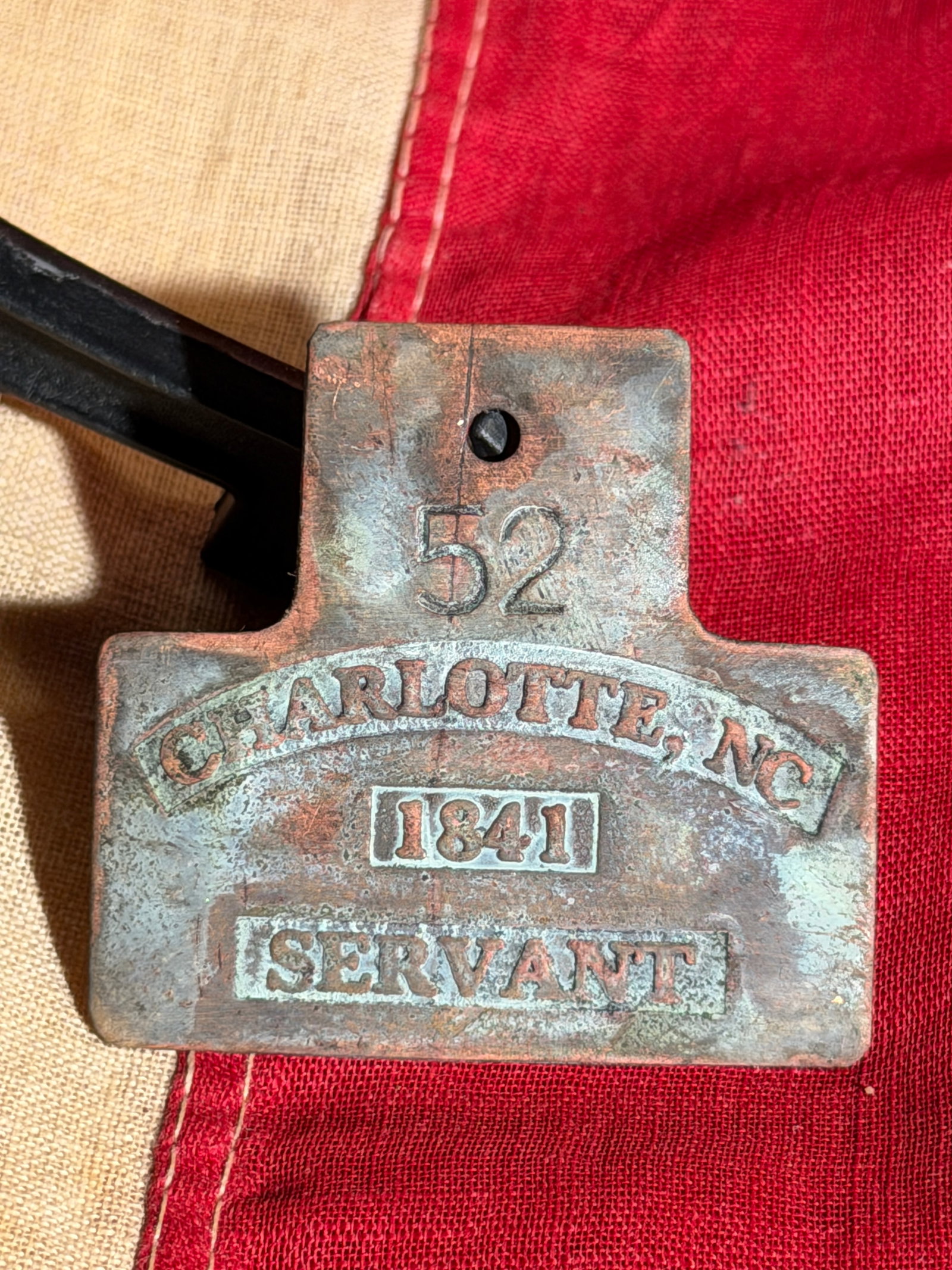 Slave Hire Badge for a Servant, Charlotte, North Carolina, No. 52 (1841): This copper badge was issued in Charlotte, North Carolina, in 1841 as part of a municipal system regulating the labor of enslaved individuals hired out by their owners. The badge is stamped “Charlot