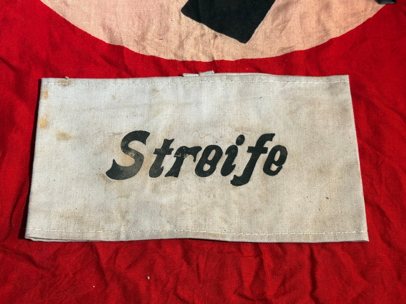 German WWII “Streife?? Military Armband: White cloth armband printed with the word “Streife” (German for “patrol”). Such armbands were worn by German personnel during the Second World War to identify individuals assigned to p