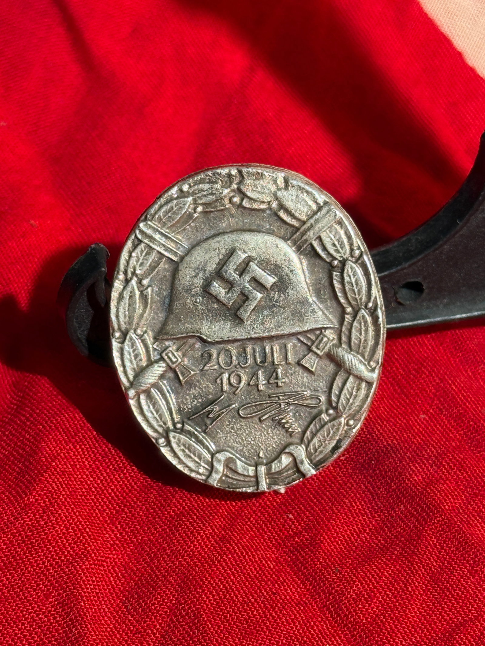 German WWII “20 July 1944?? Wound Badge (20. Juli Verwundetenabzeichen) Marked 30: Silver-colored metal badge featuring a German steel helmet bearing a swastika, surrounded by a laurel wreath with the inscription “20 Juli 1944.” This special wound badge was instituted by Ado