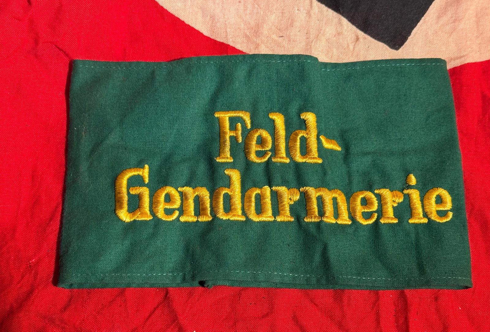German WWII Feldgendarmerie Armband With RZM Paper Tag: Green cloth armband embroidered in gold thread with the words “Feld-Gendarmerie,” identifying members of the German military police during the Second World War. The interior retains an RZM (Re