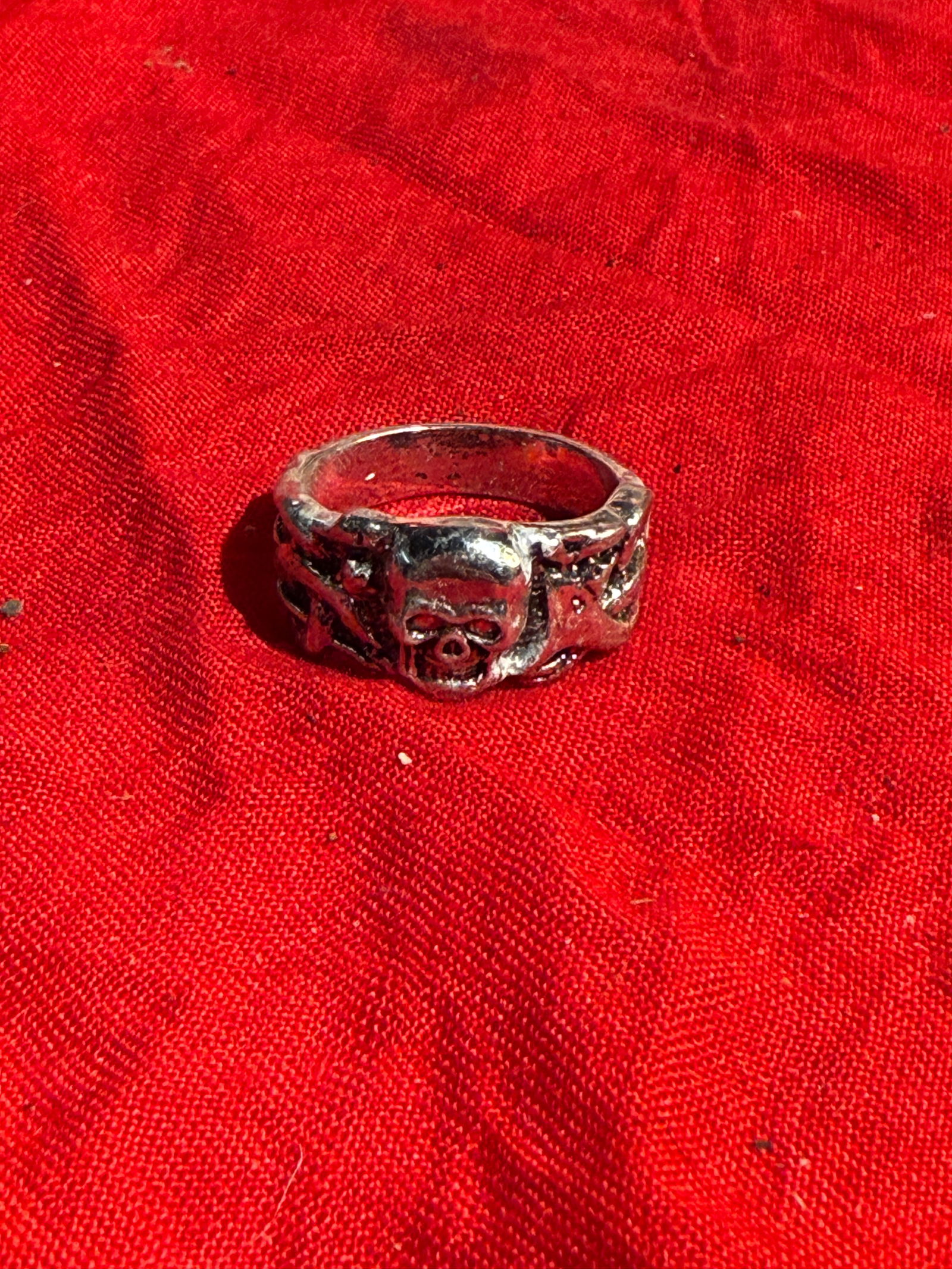 WW2 German Totenkopf Skull and Crossbones Motif Ring: Cast metal ring featuring a raised skull and crossbones motif at the front, with decorative relief detailing along the band. Rings with skull imagery have long been used as memento mori symbols, repre