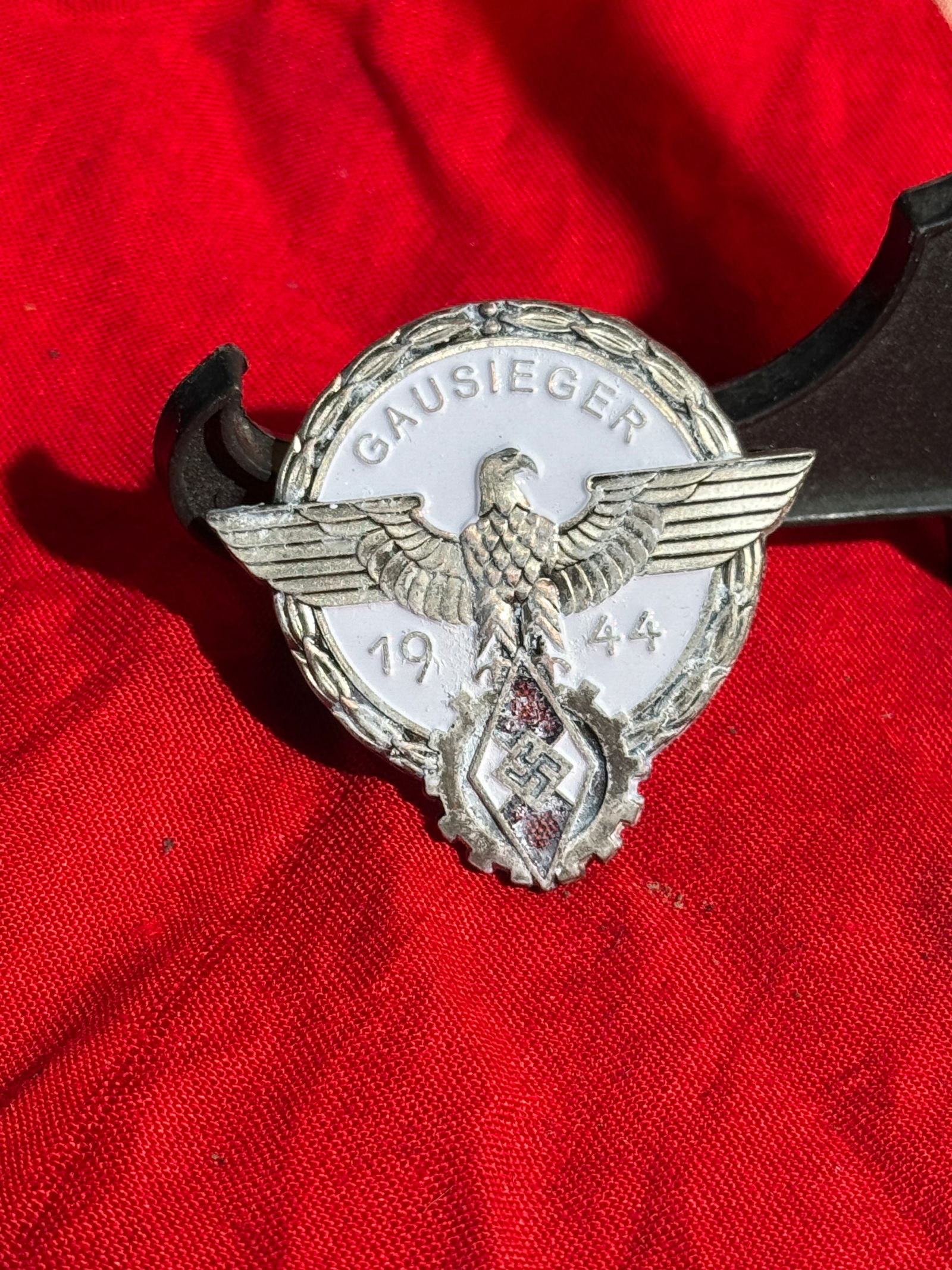 WW2 German “Gausieger 1944?? Hitler Youth Achievement Badge By C. Brehmer: Circular metal badge with white enamel center inscribed “GAUSIEGER 1944,” featuring a spread-winged eagle and the Hitler Youth diamond emblem with swastika below. The term Gausieger (“distri