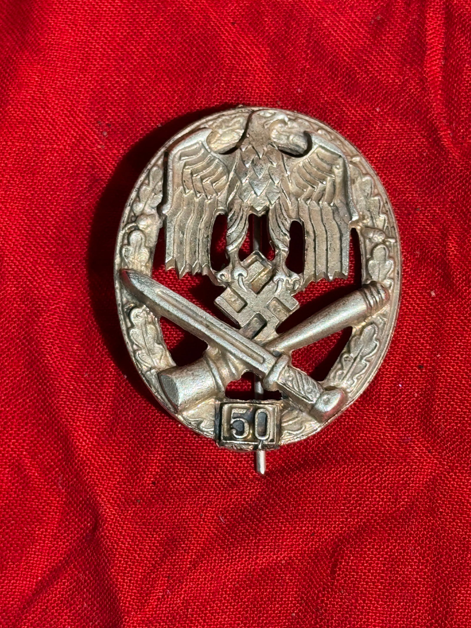 WW2 German General Assault Badge with “50?? Engagement Clasp, Nazi Germany, c. 1943–1945 By RZM: Oval zinc badge featuring the German national eagle above crossed bayonet and stick grenade within an oak-leaf wreath, with a “50” clasp at the base indicating participation in fifty combat as