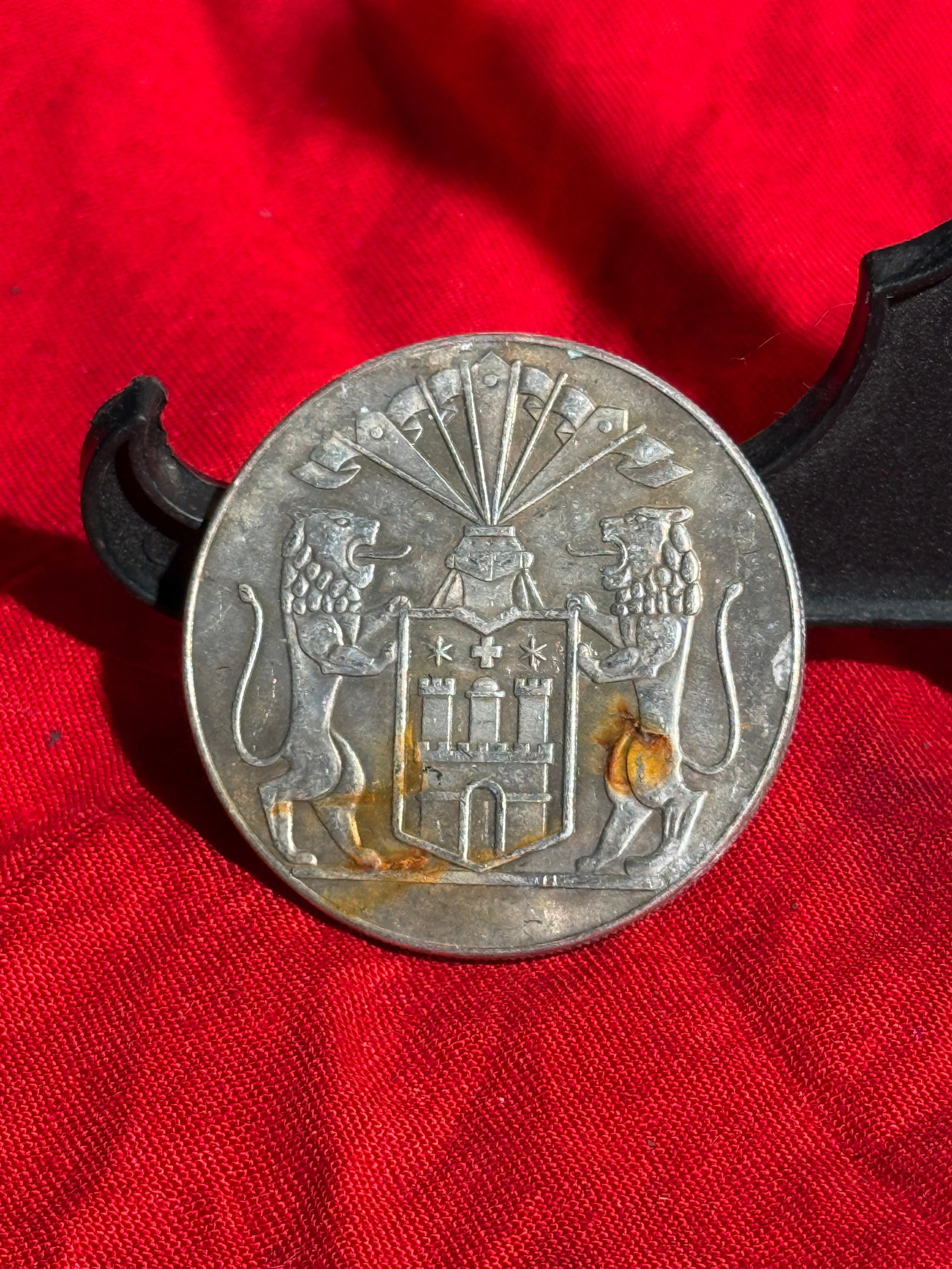 WW2 German Nazi Propaganda Medallion Featuring the Arms of Hamburg, Germany, c. 1930s–1940s: Round metal commemorative medallion incorporating the Greater Coat of Arms of the Free and Hanseatic City of Hamburg, depicting a castle shield supported by two lions beneath a helmet and banners. The