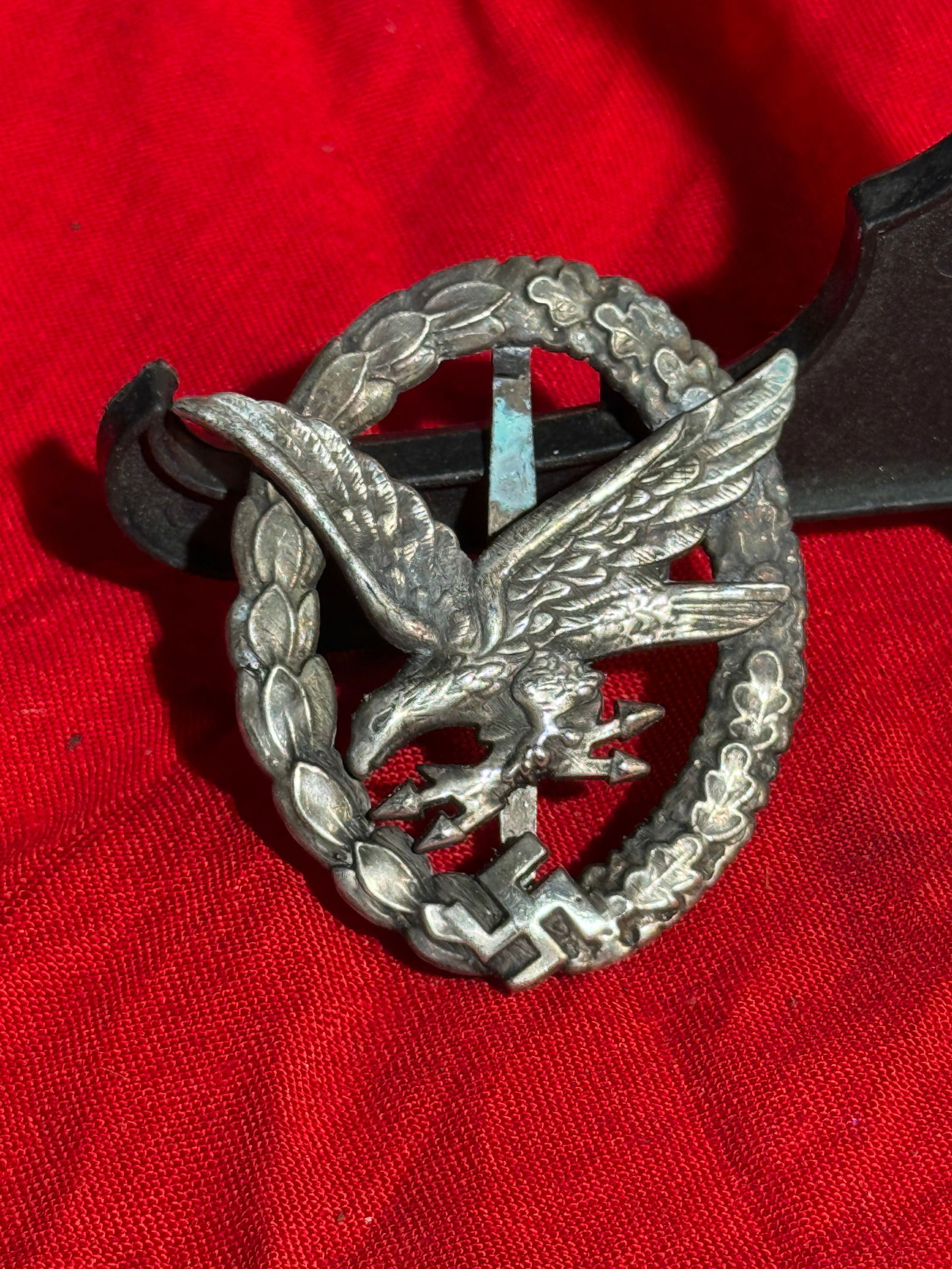 WW2 German uftwaffe Flak War Badge, Germany, c. 1941–1945 By B&NL: Silvered metal badge awarded to Luftwaffe anti-aircraft artillery personnel for combat service. The design depicts a diving eagle clutching lightning bolts within an oak-leaf wreath, with a swastika a
