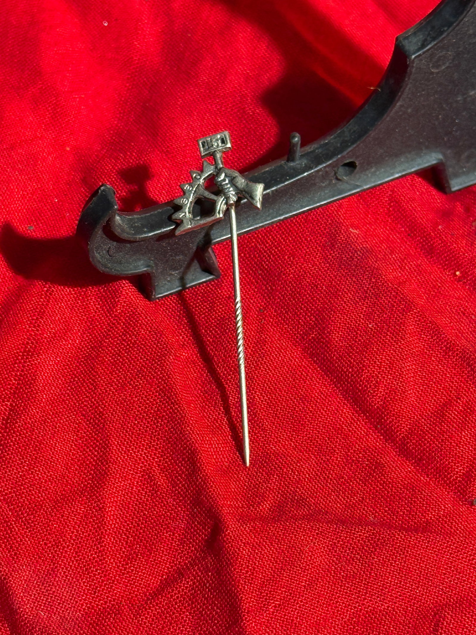 WW2 German Industrial Worker Stick Pin: Small metal lapel stick pin depicting a worker holding a hammer beside a gear wheel, symbols commonly associated with industrial labor and mechanical trades. A small banner appears above the figure, l