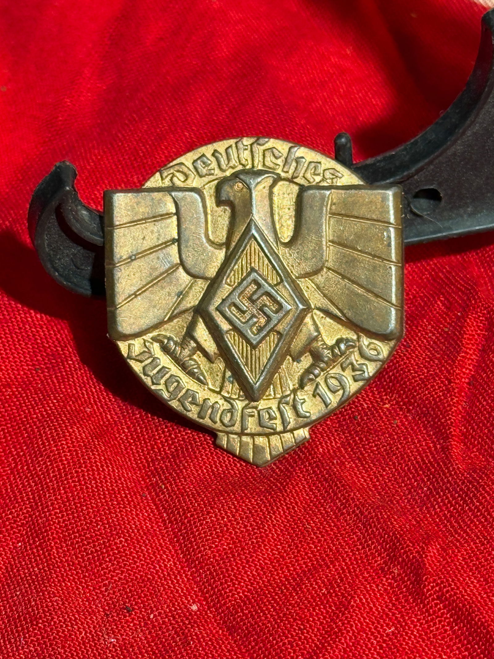 WW2 Hitler Youth “Deutschland Erwache?? Badge, c. 1930s: Metal badge featuring a spread-winged eagle over the Hitler Youth diamond emblem with swastika, surrounded by the inscription “Deutschland Erwache” (“Germany Awake”), a slogan associat