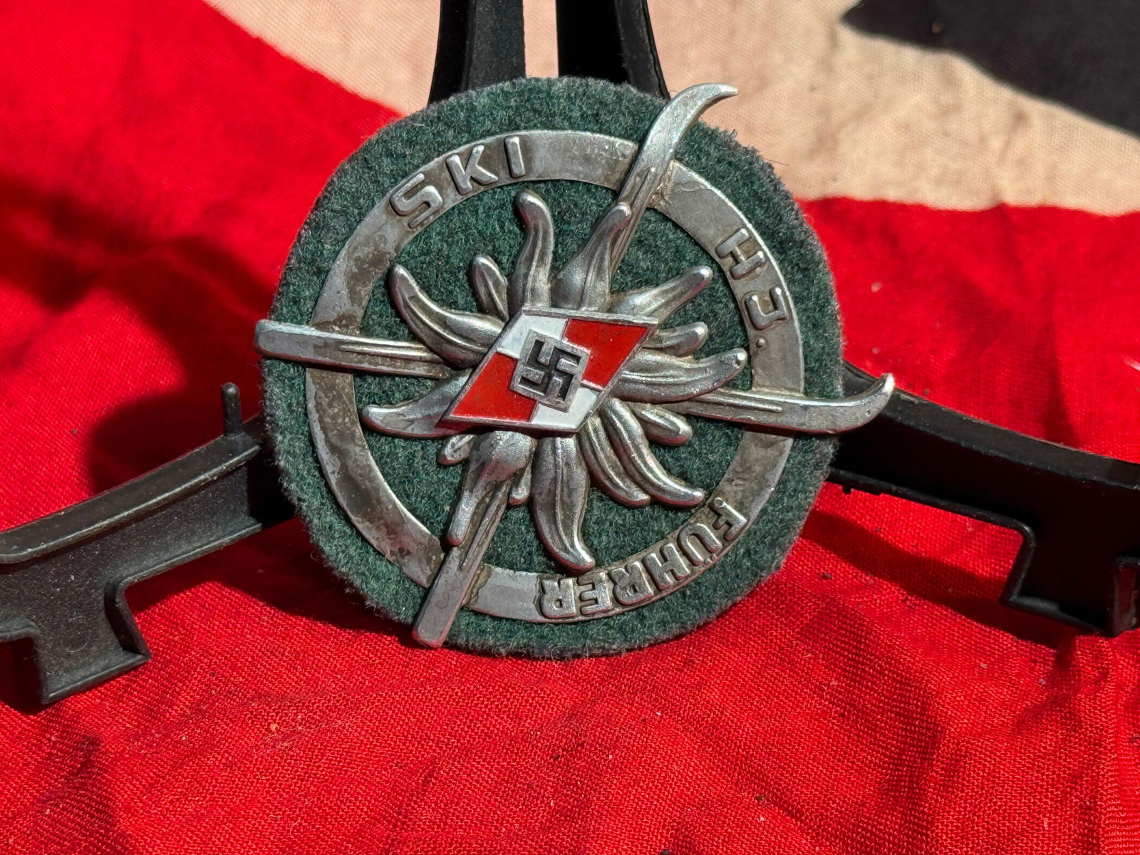 WW2 German NS-Reichsbund für Leibesübungen (NSRL) Ski Badge By Wittmann Munchen: Circular German winter sports badge associated with Nazi-era ski organizations, featuring crossed skis over an edelweiss flower, a symbol commonly linked to alpine sports and mountain troops. At the c
