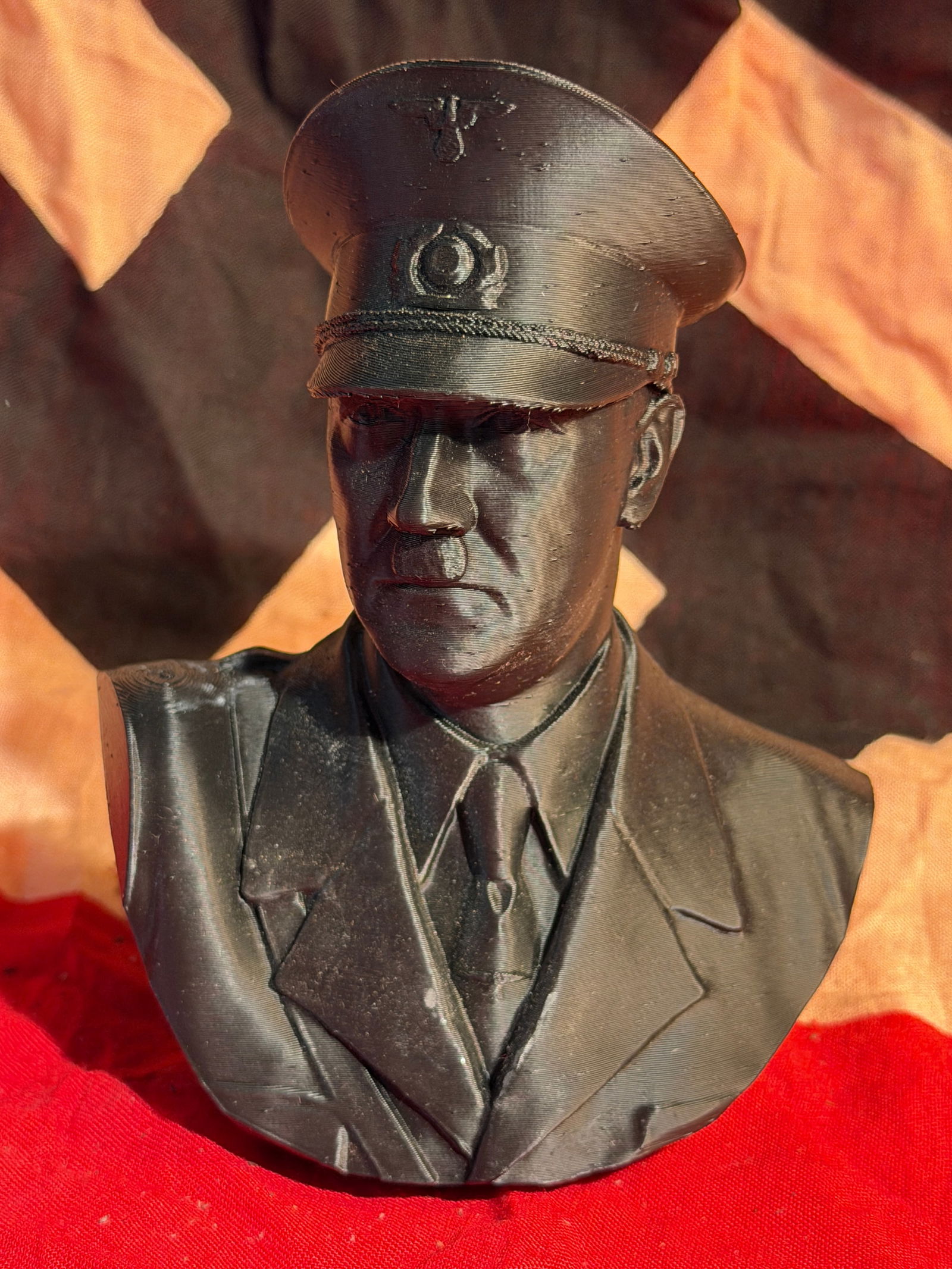 WW2 German Bust of Adolf Hitler in Military Uniform: Small sculpted bust depicting Adolf Hitler (1889–1945) wearing a military-style tunic and peaked cap bearing the German national emblem used during the Third Reich. The sculpture presents Hitler wit