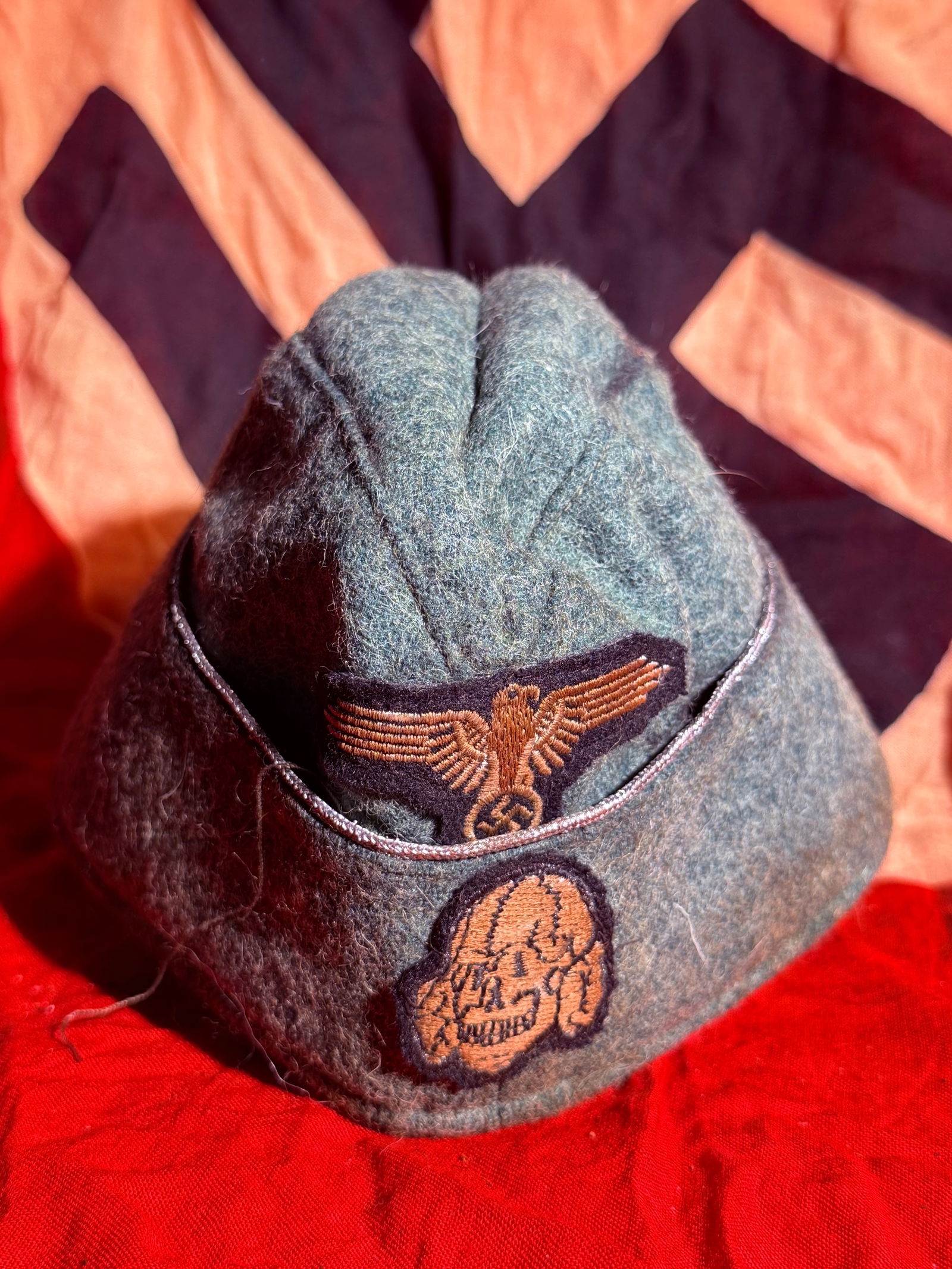 WW2 German SS Field Cap (SS Feldmütze) with Totenkopf Insignia, Germany, c. 1930s–1945 With RZM: Wool field cap associated with the Schutzstaffel (SS) of Nazi Germany, constructed in gray-green cloth typical of wartime field uniforms. The cap displays two embroidered insignia on the front: the na