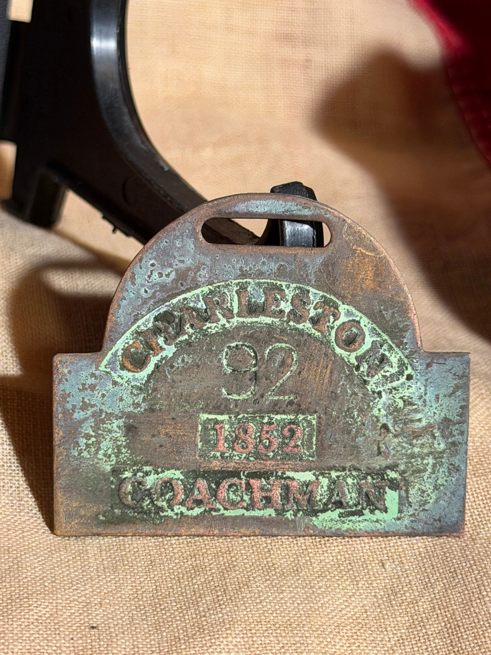 Coachman Identification Badge – Charleston, South Carolina, 1852 Slave Tag: This copper alloy identification badge is inscribed “CHARLESTON / 92 / 1852 / COACHMAN.” Badges of this type were issued by the city of Charleston, South Carolina, during the antebellum