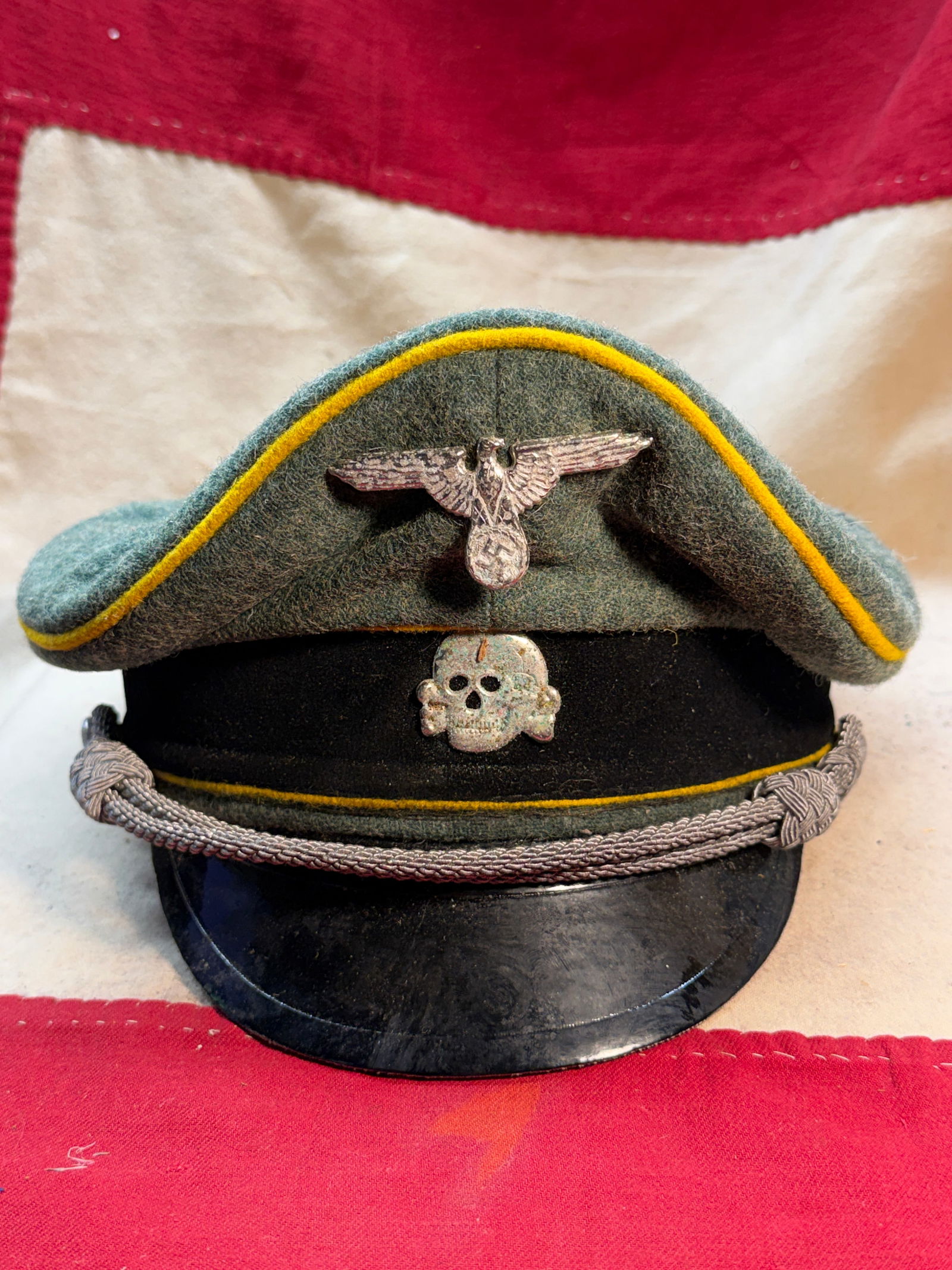 Rare WW2 German Waffen-SS Officer’s Field Cap (Schiffchen): This German Waffen-SS field cap, commonly known as a Schiffchen or overseas cap, was worn by members of the Waffen-SS during the Second World War. Constructed of field-gray wool with yellow piping, th