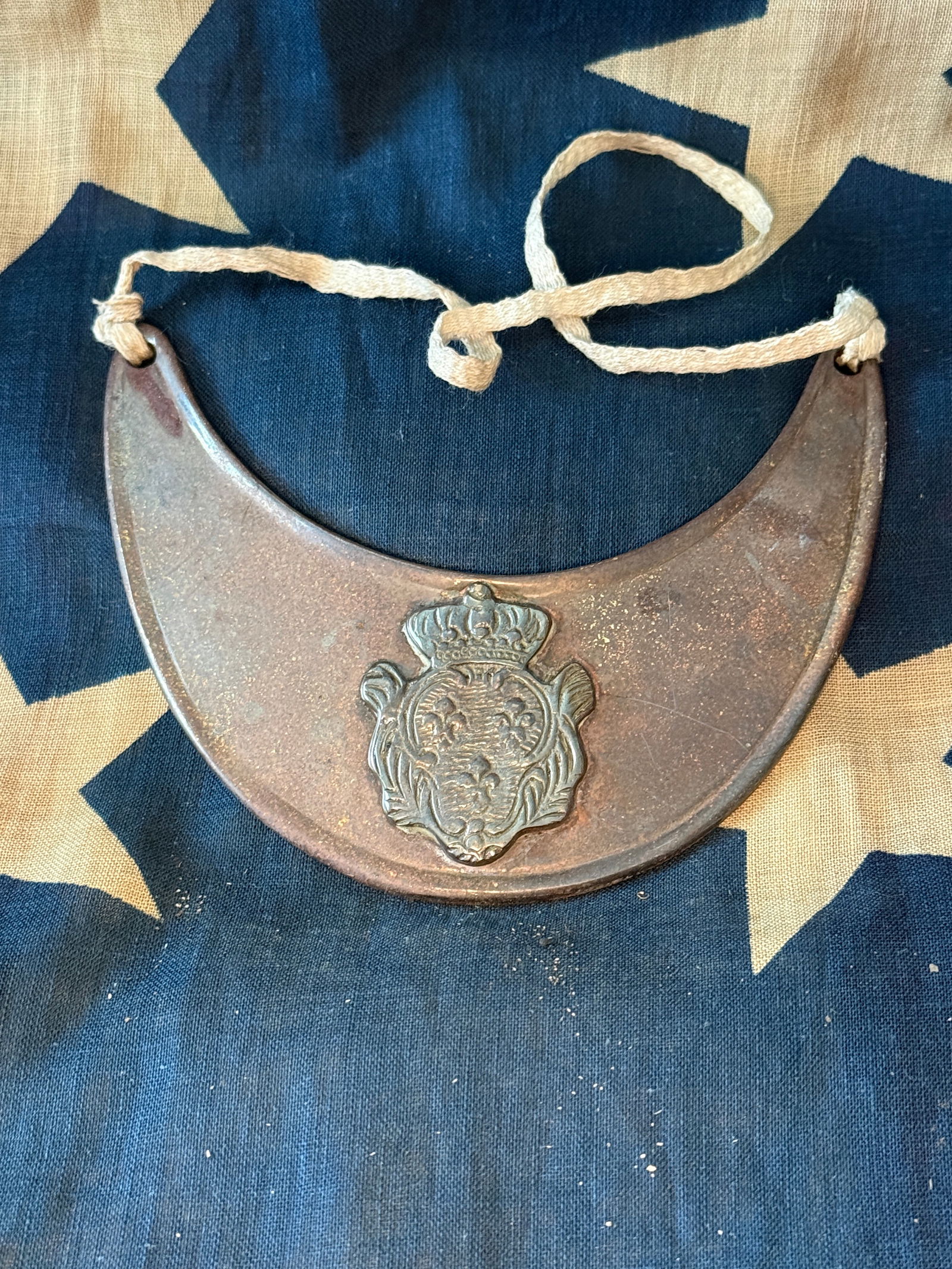 Revolutionary War Officer’s Gorget with Crowned Royal Coat of Arms: 18th-century officer’s gorget, a crescent-shaped throat plate worn as a symbol of rank during the Revolutionary War era. Crafted of copper or brass, this example features an applied crowned coat of