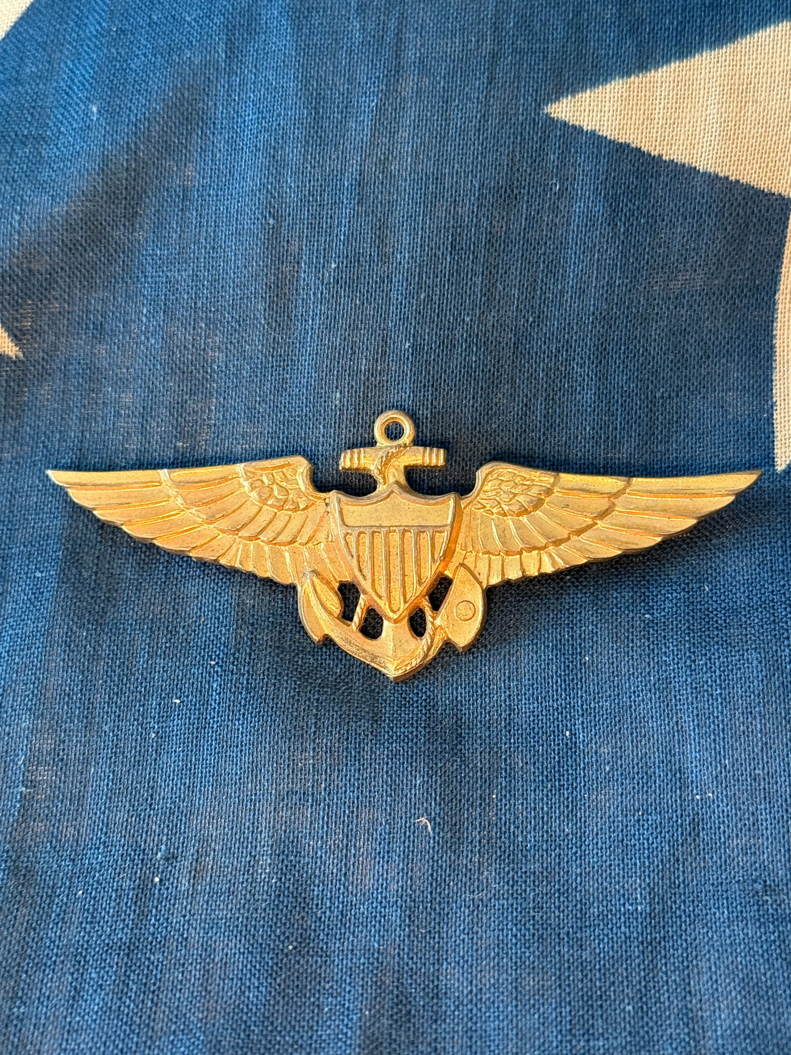 WW2 United States Naval Aviation Insignia (Naval Aviator Wings): This gilt metal badge represents the qualification insignia worn by United States Naval Aviators. The design features a central shield with vertical stripes, flanked by outstretched wings and superimp