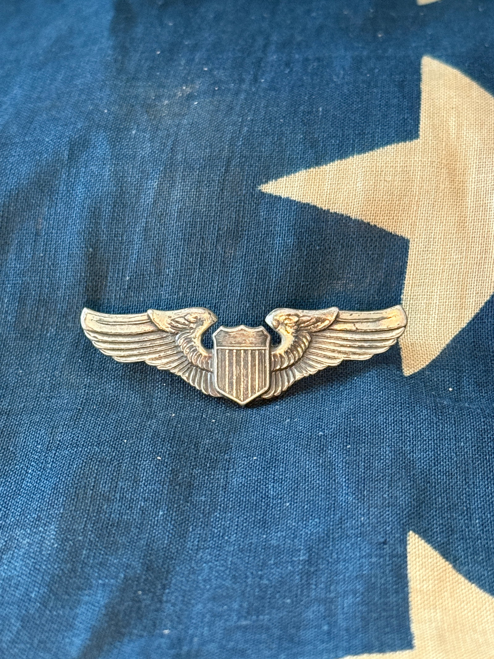 WW2 United States Army Air Forces Pilot Qualification Wings In Sterling Silver: This metal badge represents the qualification insignia of a pilot in the United States Army Air Forces during the Second World War period. The design features outstretched wings flanking a central shi