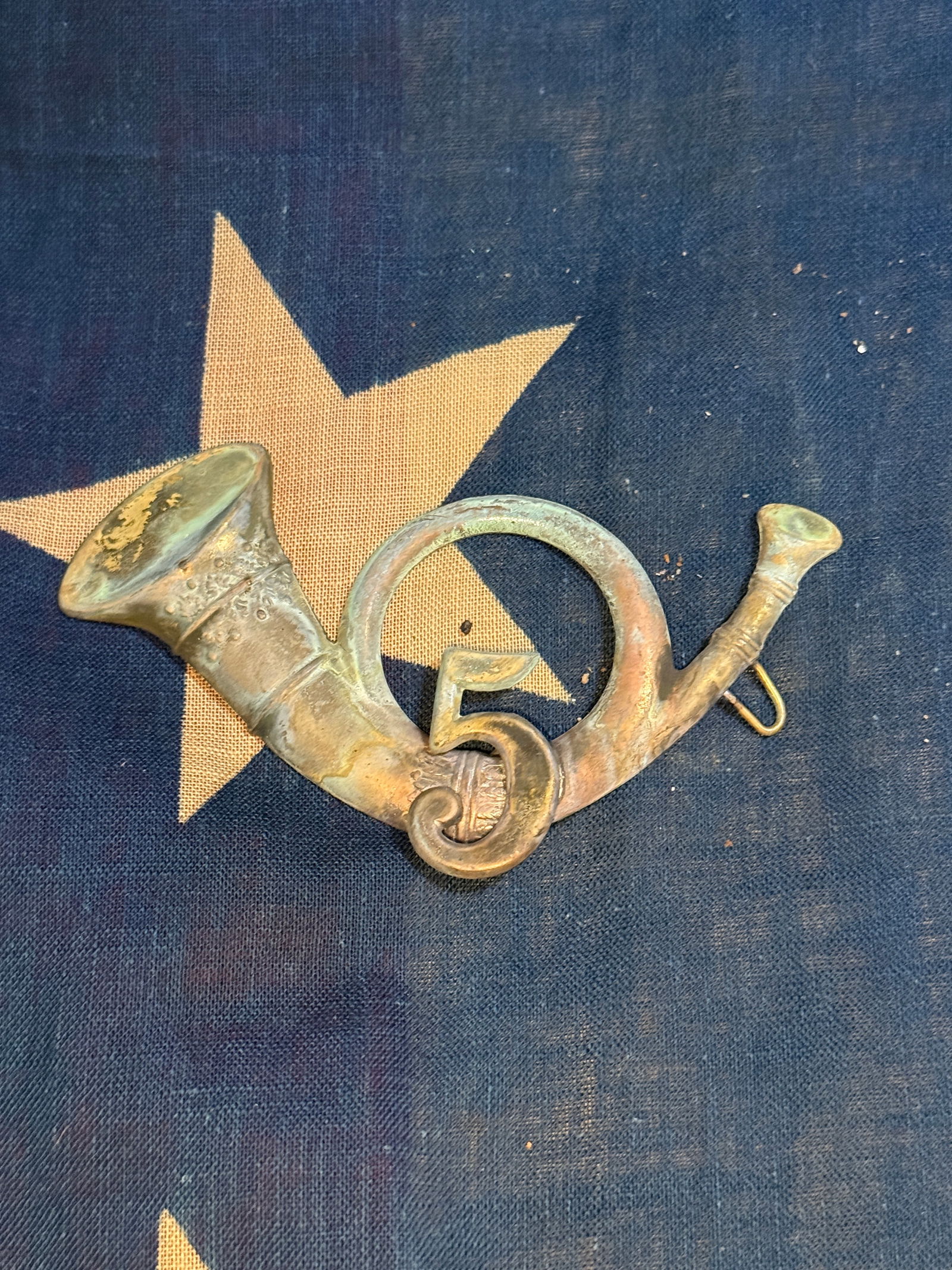Civil War–Era Infantry Bugle Insignia with “5?? Regimental Number: This small brass insignia represents the traditional infantry bugle horn emblem used by American military units during the mid-19th century, particularly around the American Civil War (1861–1865). T